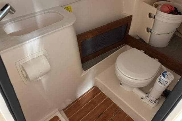 2022 Grady-White Freedom 285 boat bathroom with toilet, sink, and wooden flooring.