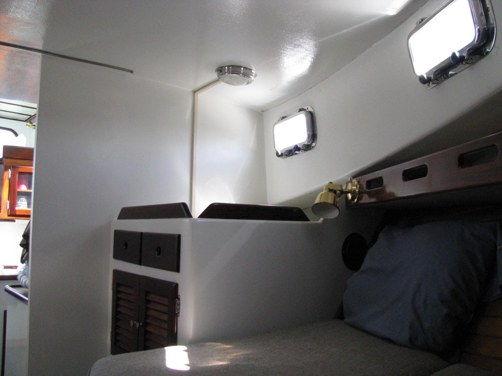 1998 Duffy 35 Downeast Cruiser cabin interior with bed, storage, and portholes.