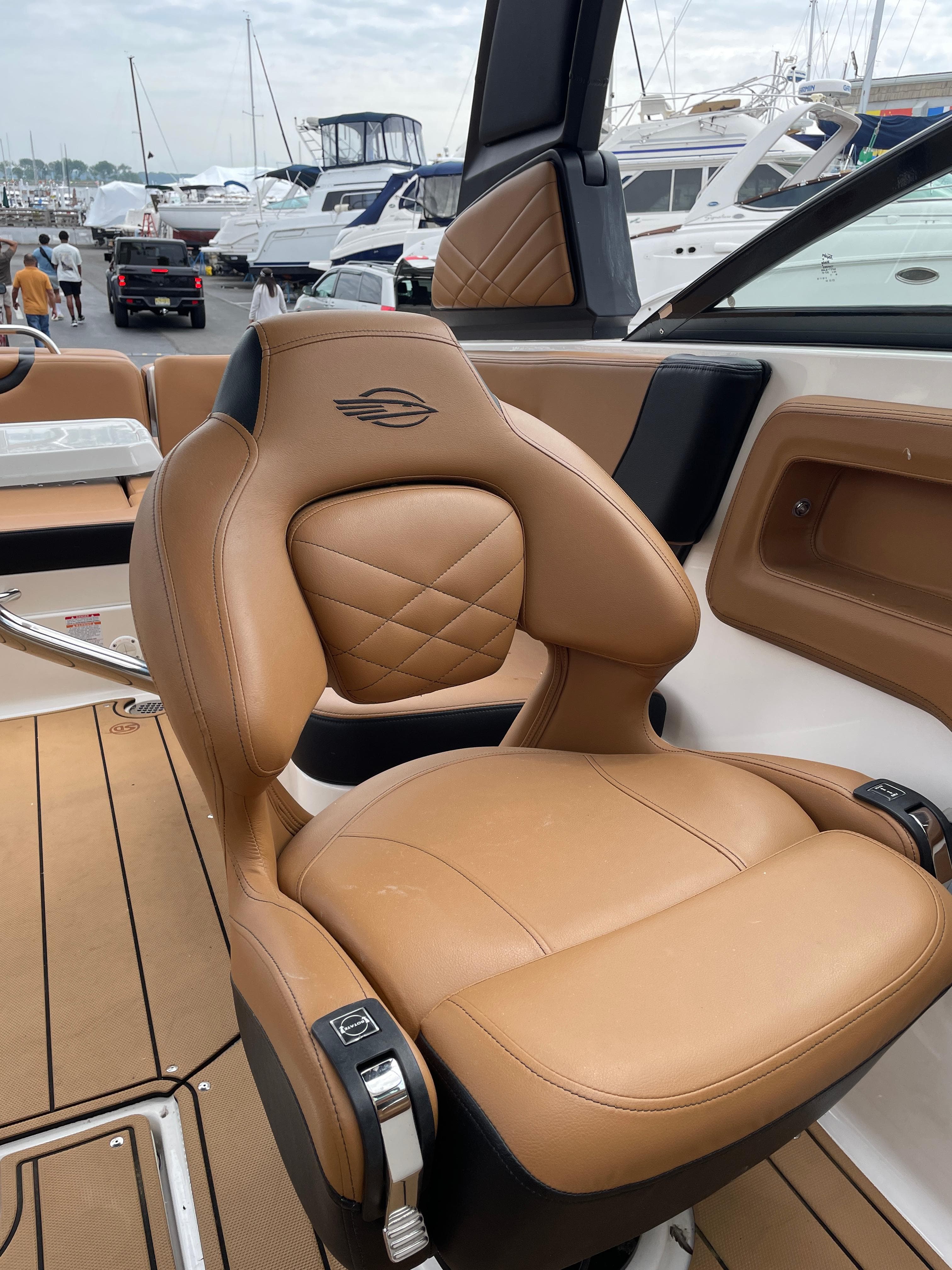Luxury tan leather seat on 2023 Chaparral 287 SSX boat, docked with other yachts.