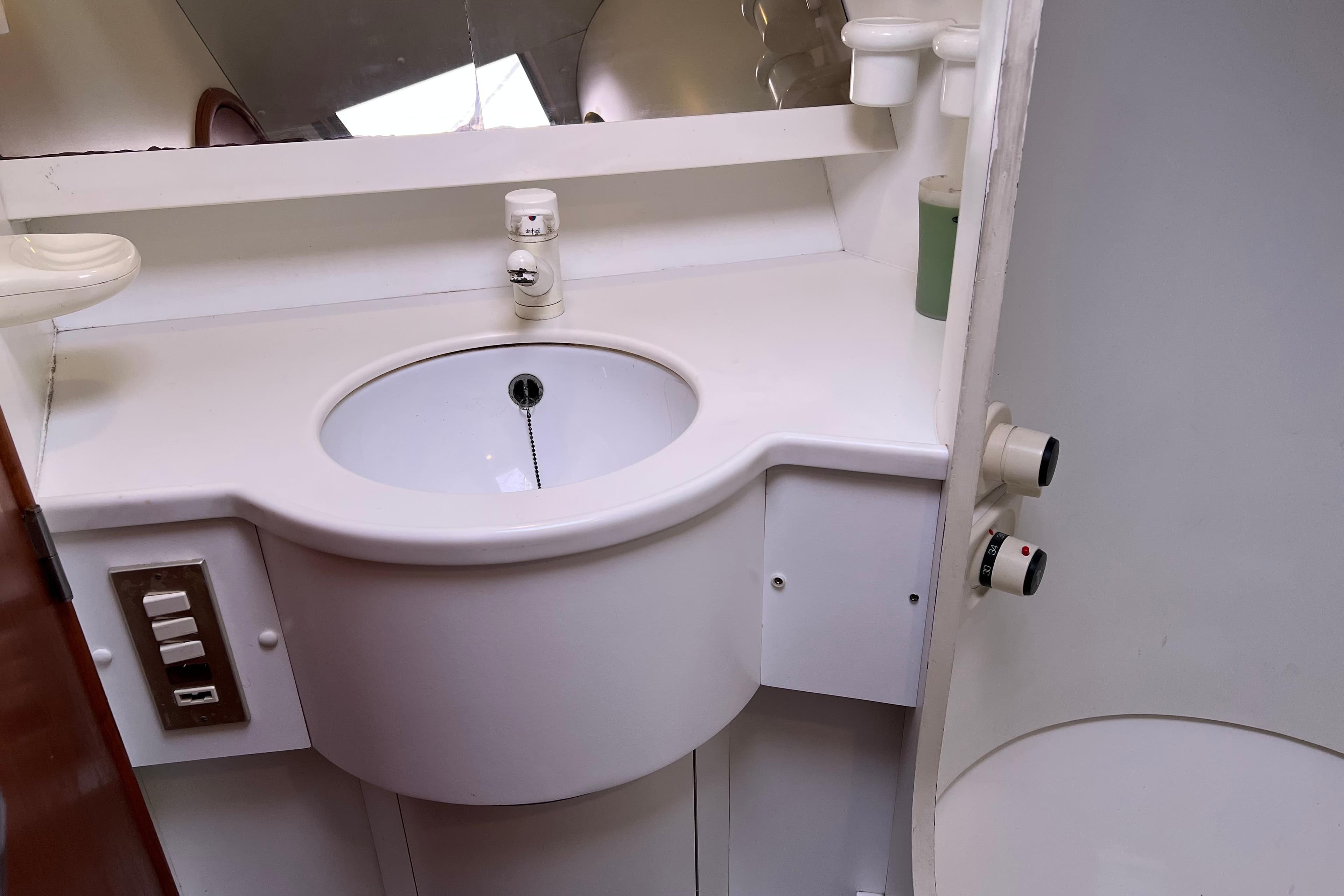 Bathroom sink area in a 1990 Trintella 49A yacht, featuring modern fixtures.