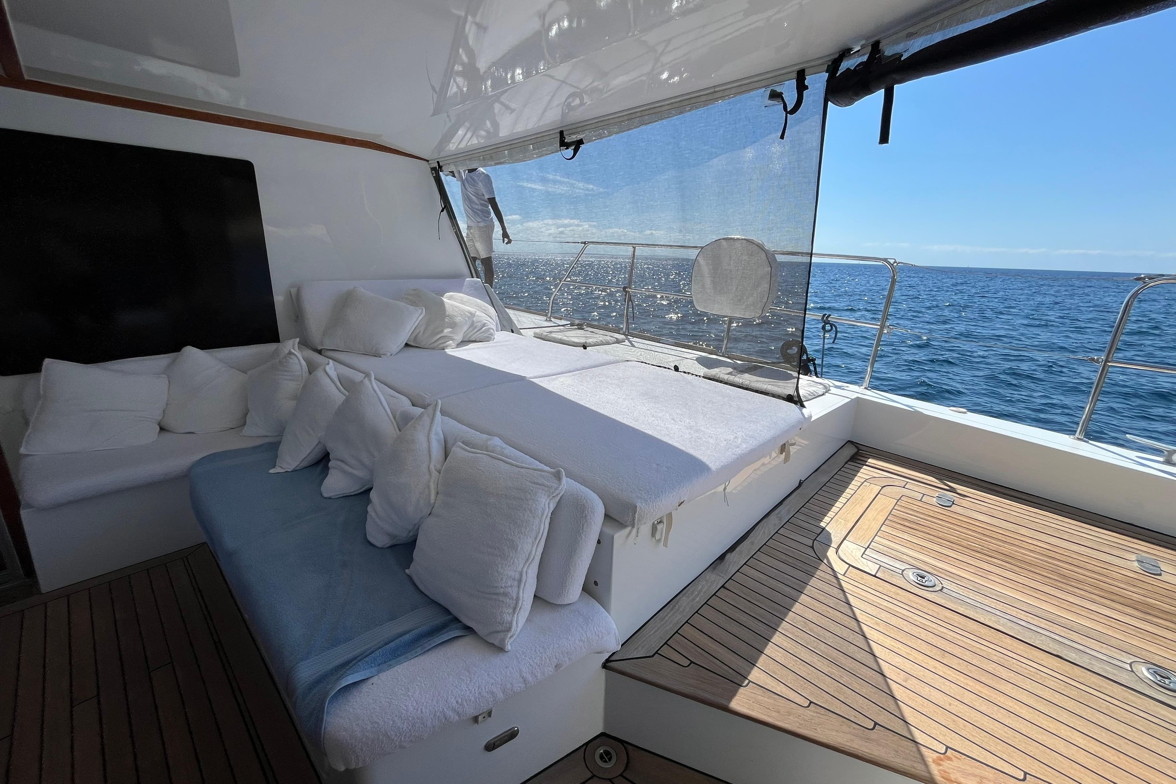Luxurious Sunreef 60 yacht deck with comfortable seating, ocean view, and sunny weather.