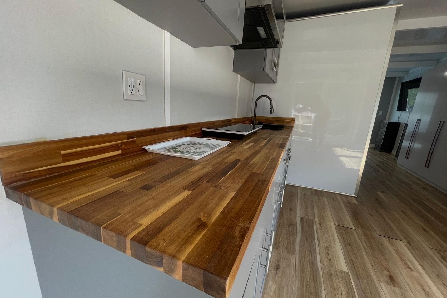 Modern kitchen with wooden countertop, sleek cabinetry, and stainless steel fixtures in a 2023 Modern Struktures MS400.