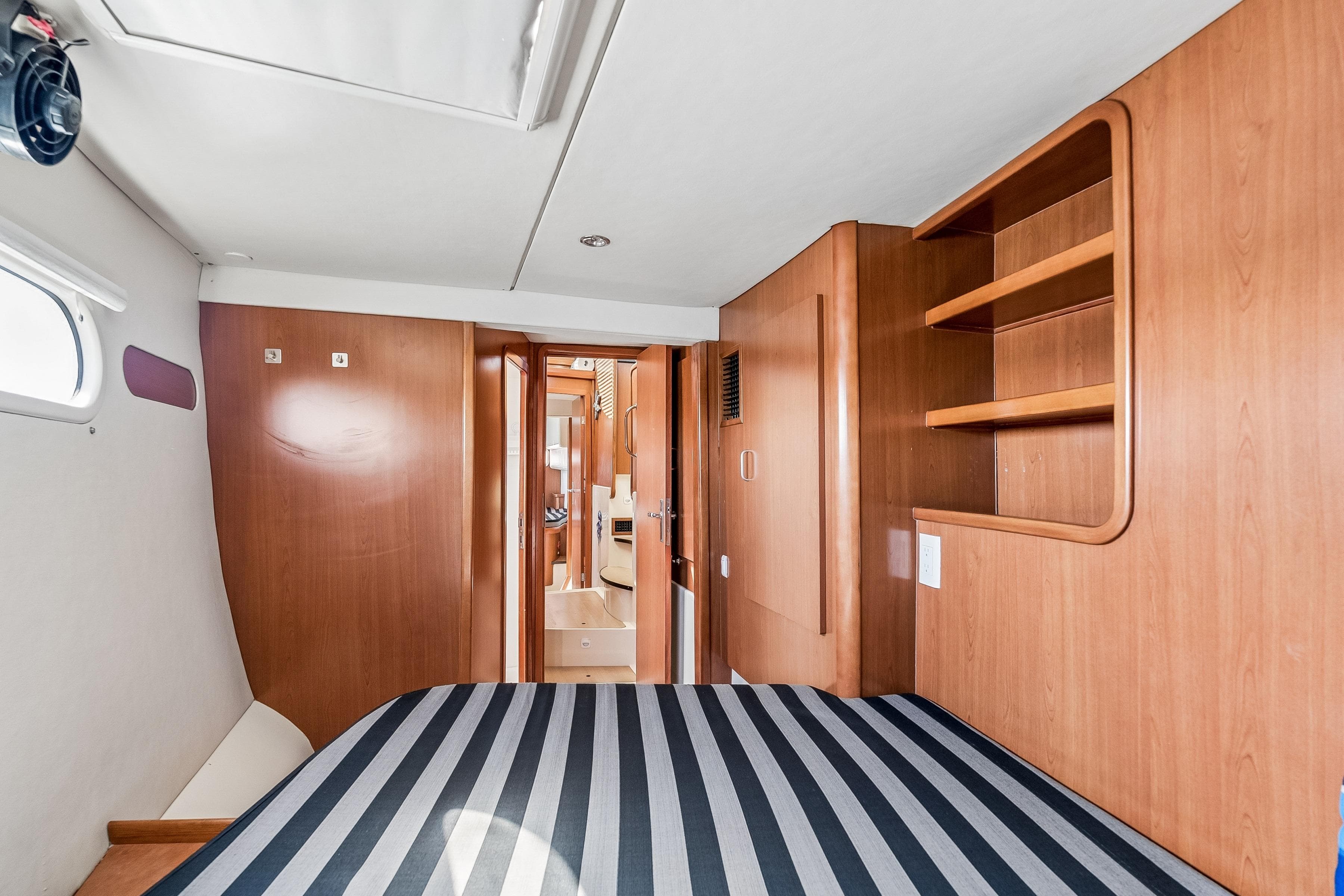 Interior of 2007 Leopard 46 yacht cabin with striped bedding and wooden shelves.