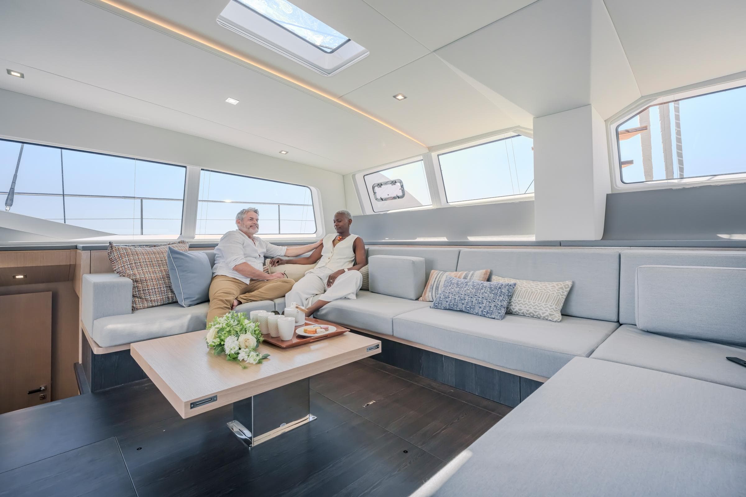 Luxurious interior of 2025 Privilege Signature 650 yacht with two people relaxing on sofas.
