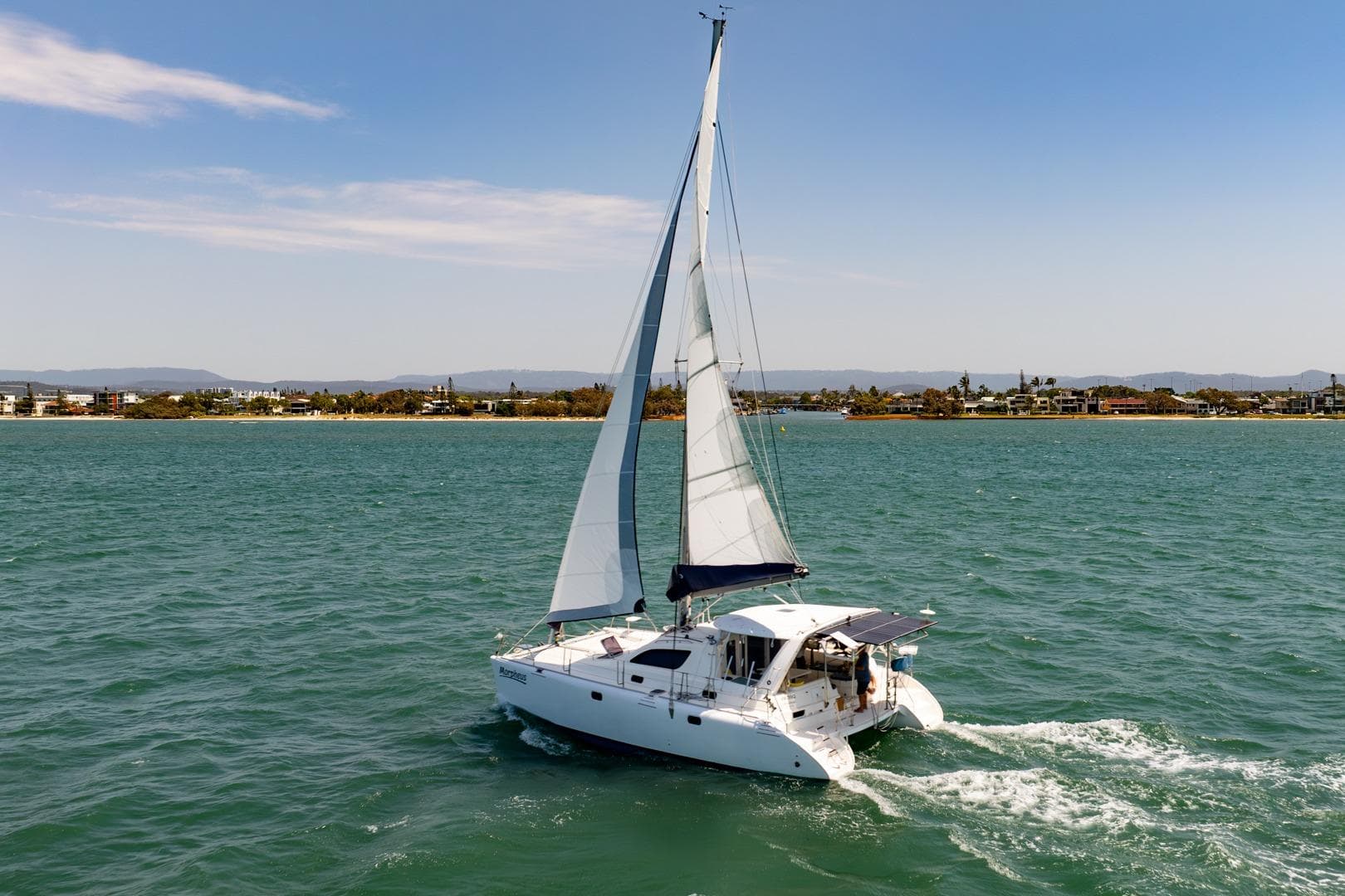 Sailing catamaran Leopard 38, 2000 model, cruising on open water near coastline.