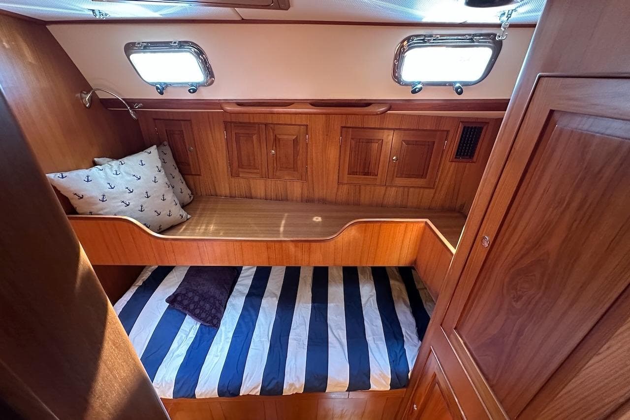 Cozy cabin interior of 2012 Hylas 56 yacht with wooden finish and striped bedding.