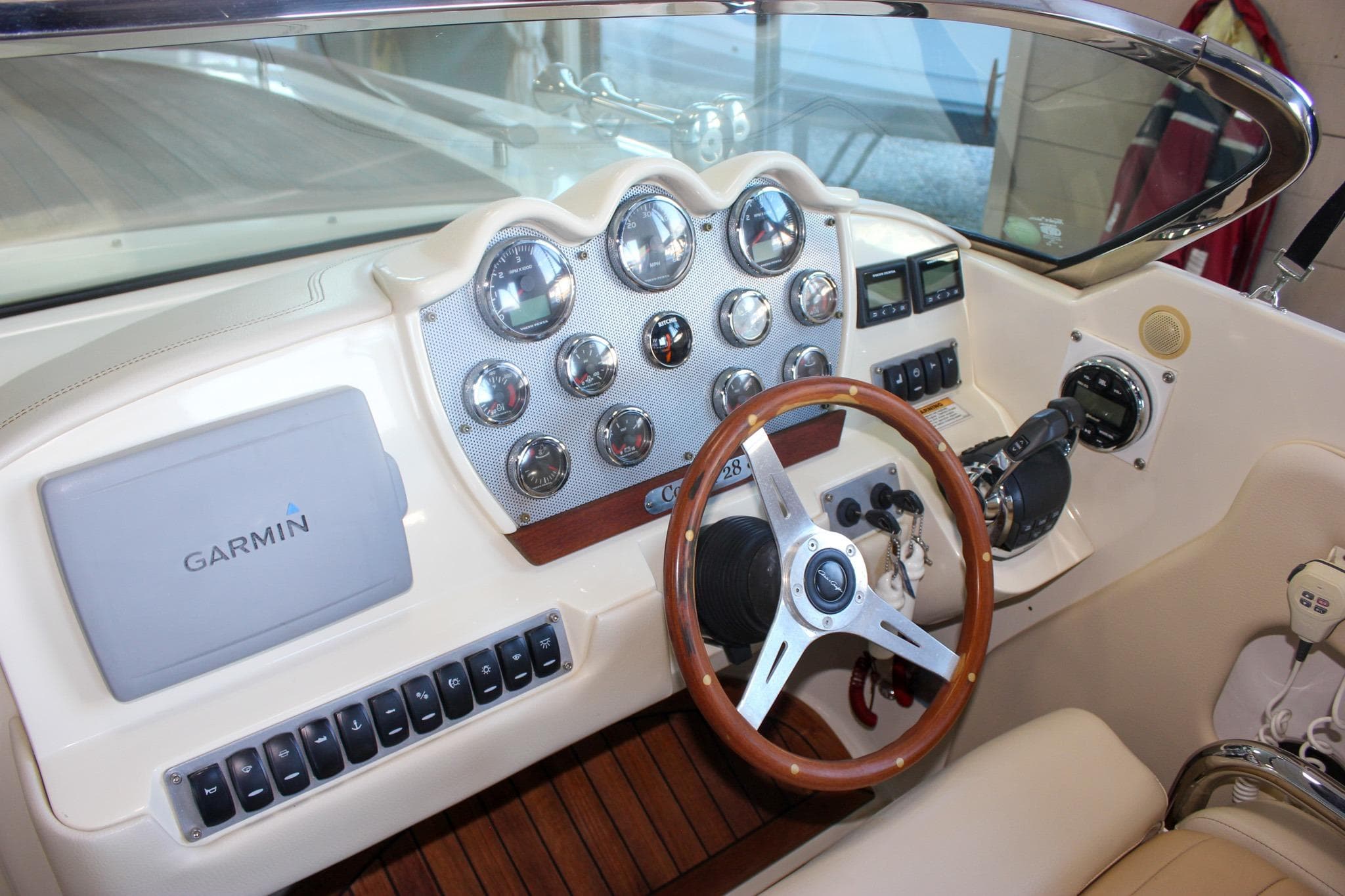 2011 Chris-Craft Corsair 28 dashboard with Garmin navigation and classic wooden steering wheel.