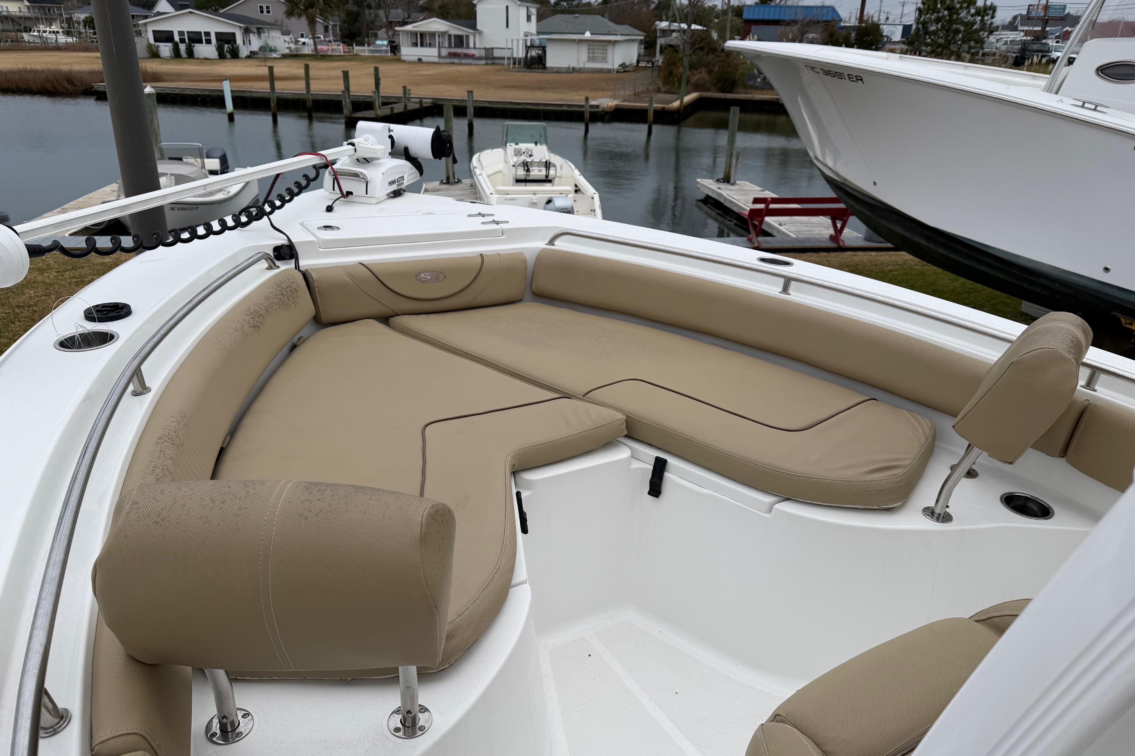 2016 Sea Hunt Ultra 234 boat with beige seating, docked near waterfront homes.