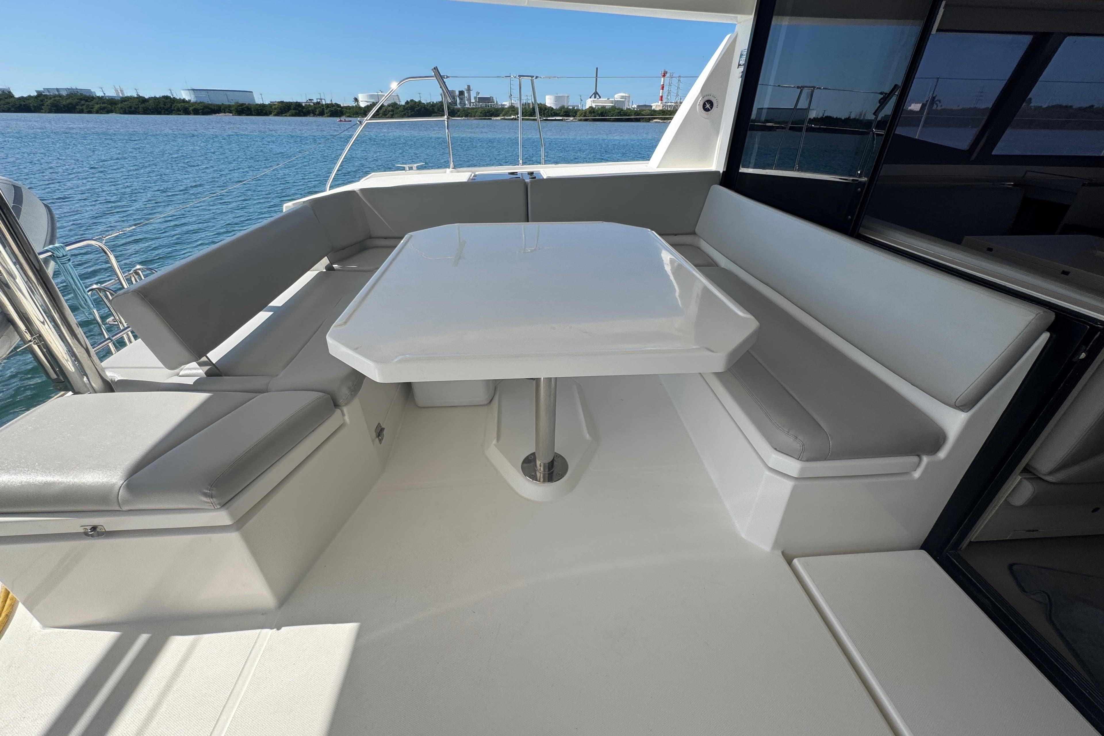 Outdoor seating area on a 2021 Leopard 45 yacht with a table and cushioned benches.