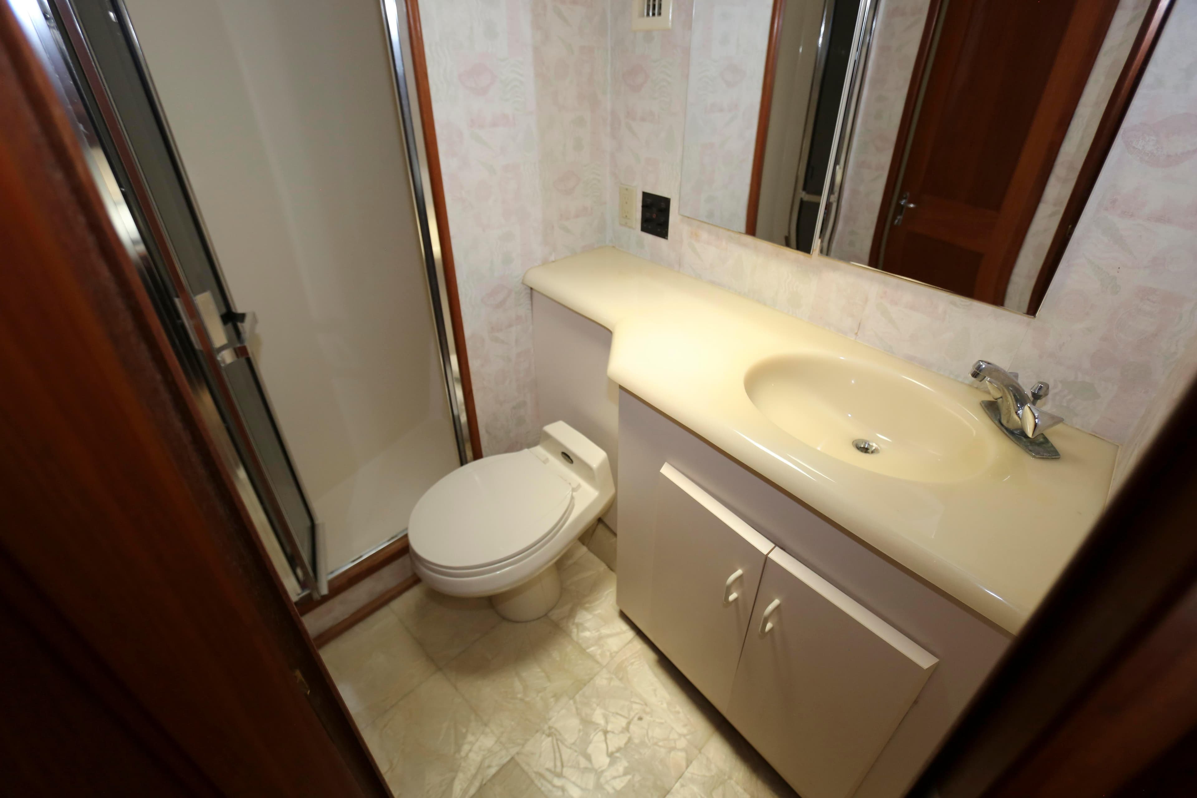 Bathroom interior of 1991 Viking 50 Convertible yacht, featuring shower, toilet, and sink.
