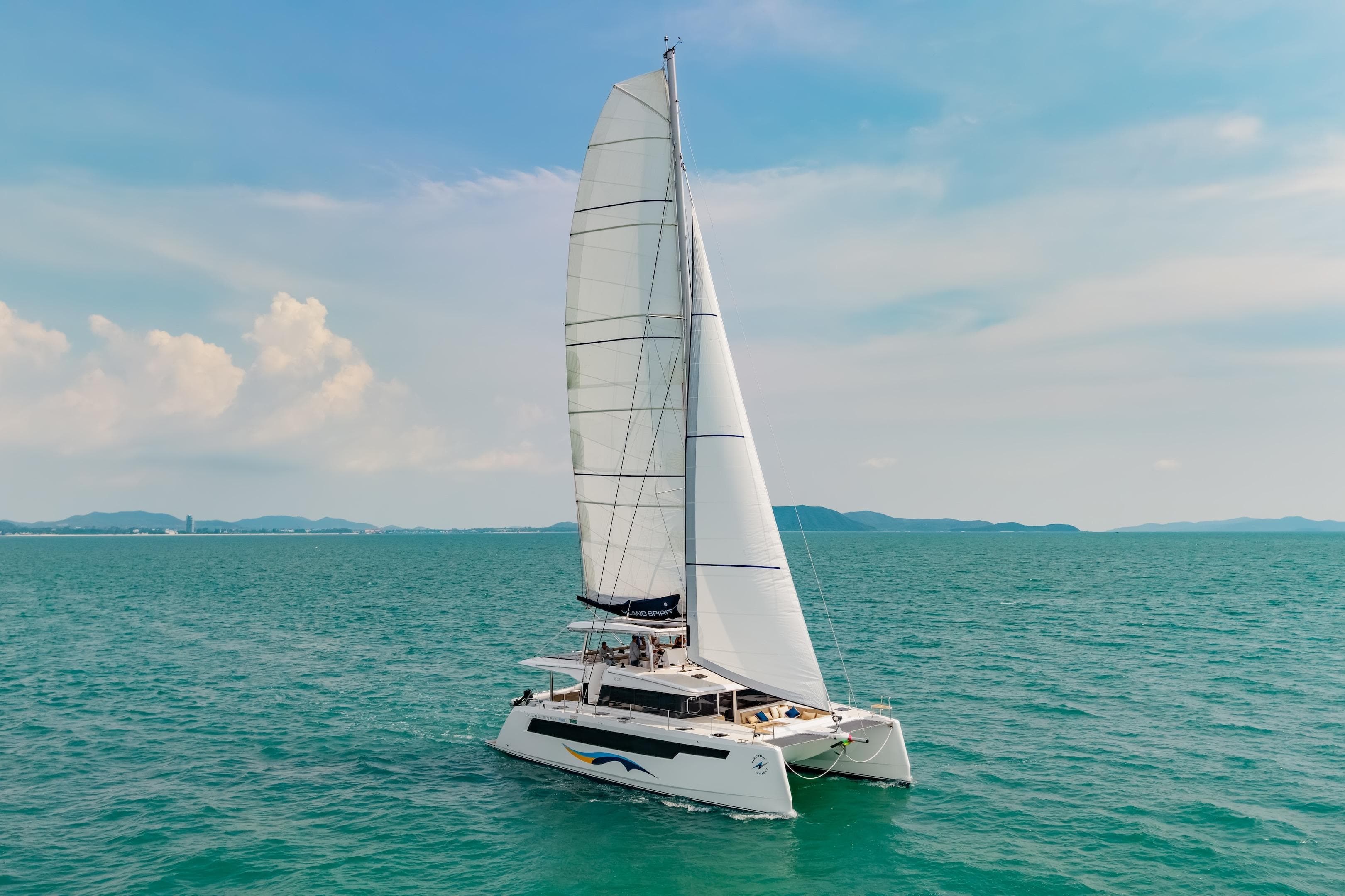 2026 Island Spirit 525E catamaran sailing on open sea under clear blue sky.