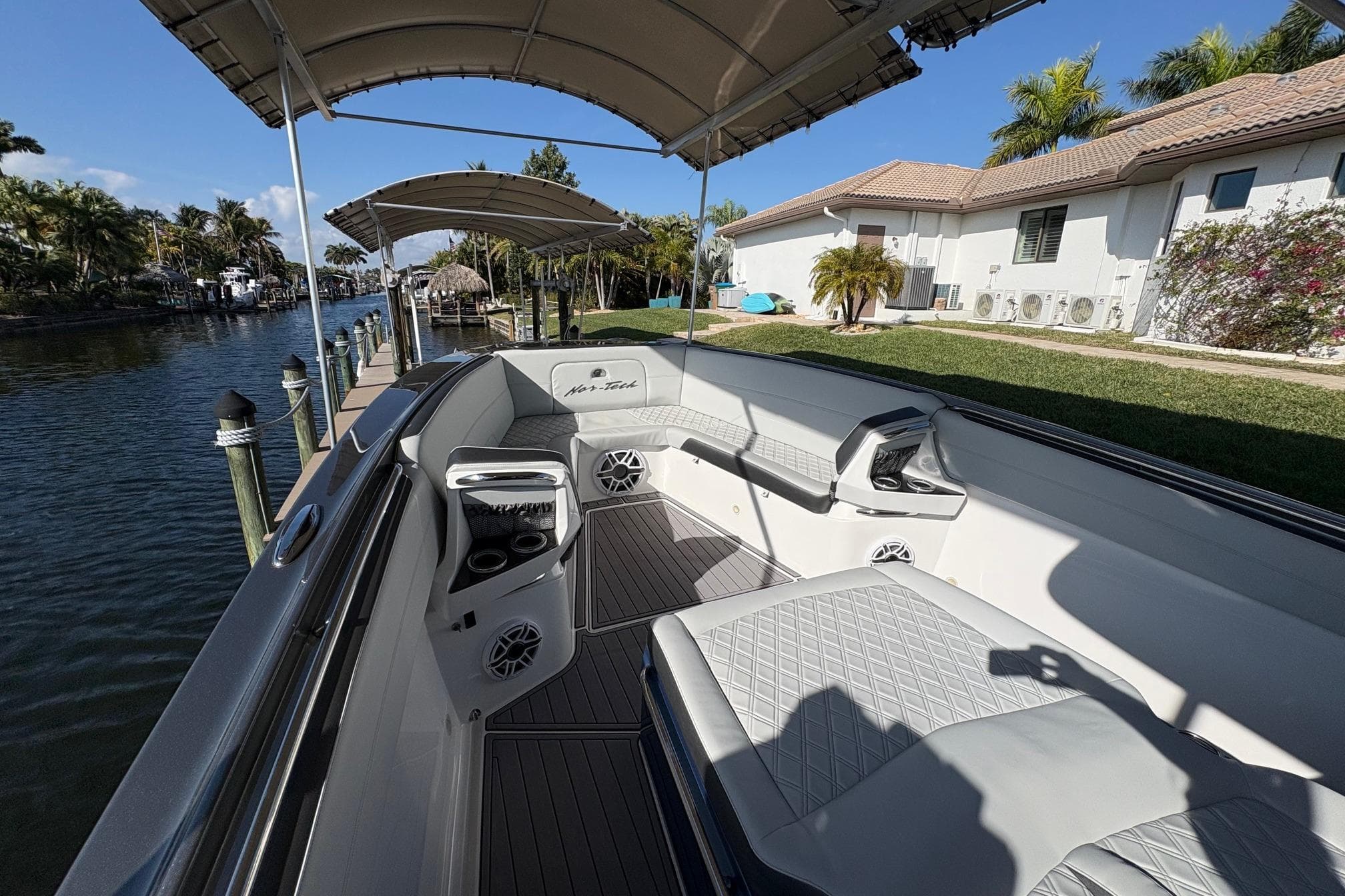 2023 Nor-Tech 390 Sport Center Console boat docked by a canal, featuring luxurious seating.