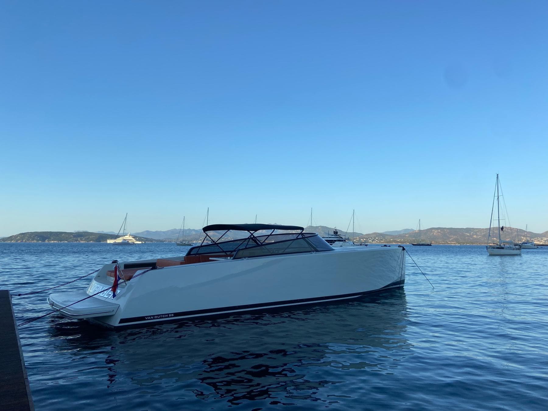 2018 VanDutch 55 yacht on calm water with distant sailboats.
