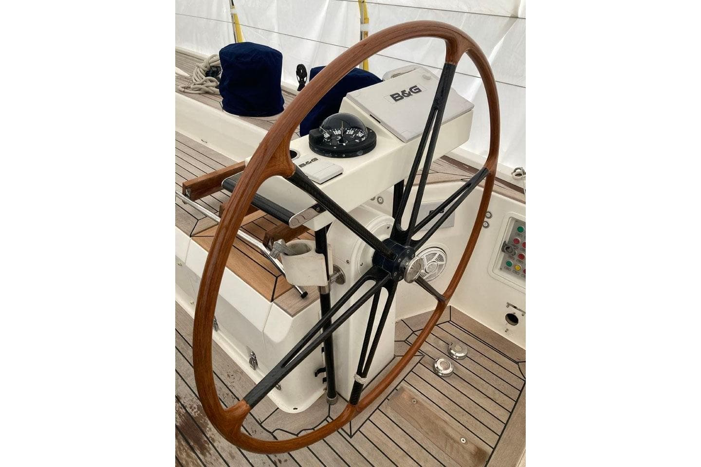 Steering wheel of 2007 Nautor Swan 75 yacht with wooden deck and navigation equipment.