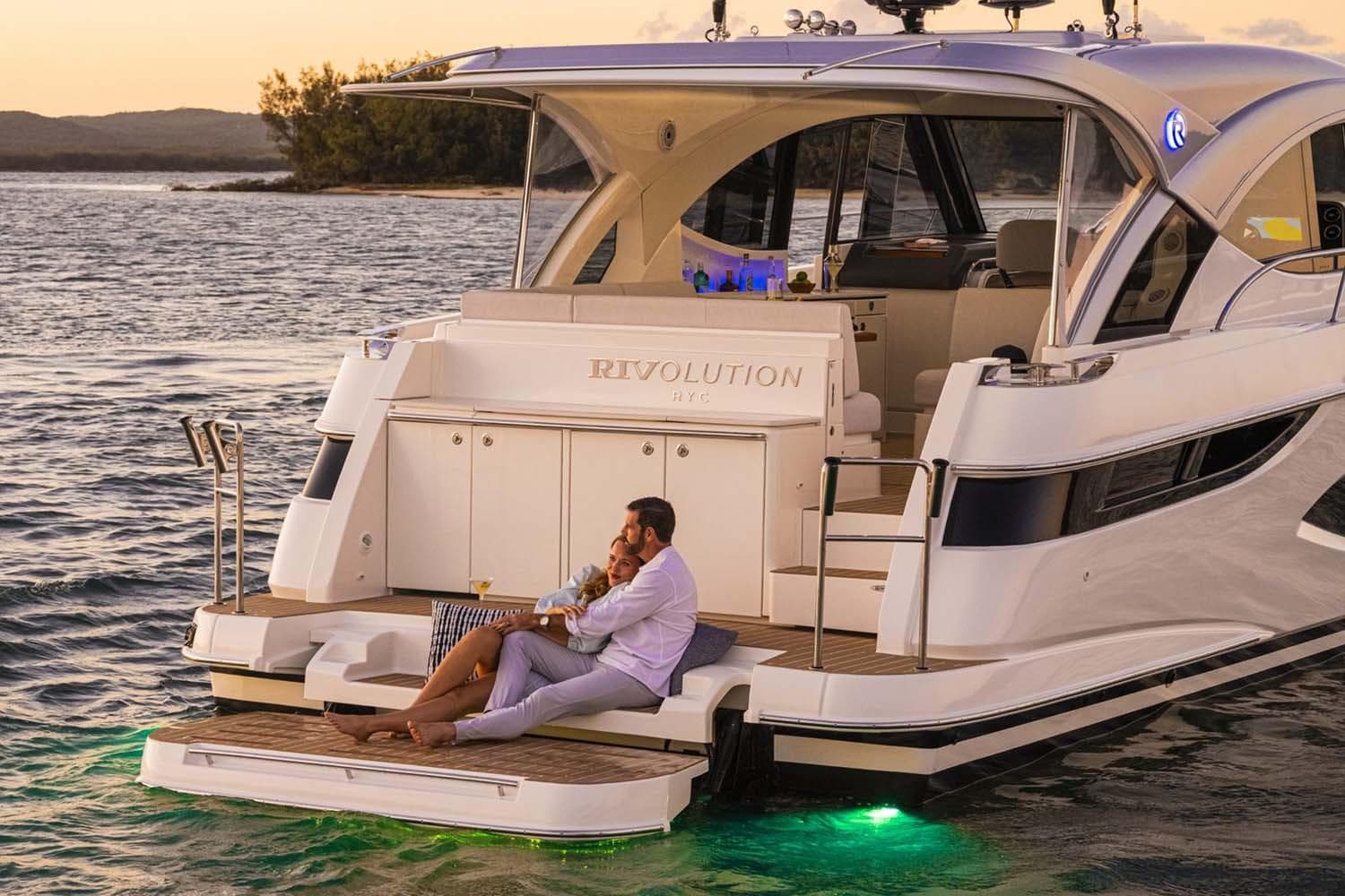 Manufacturer Provided Image: Couple relaxing on a 2026 Riviera 4300 Sport Express yacht at sunset.