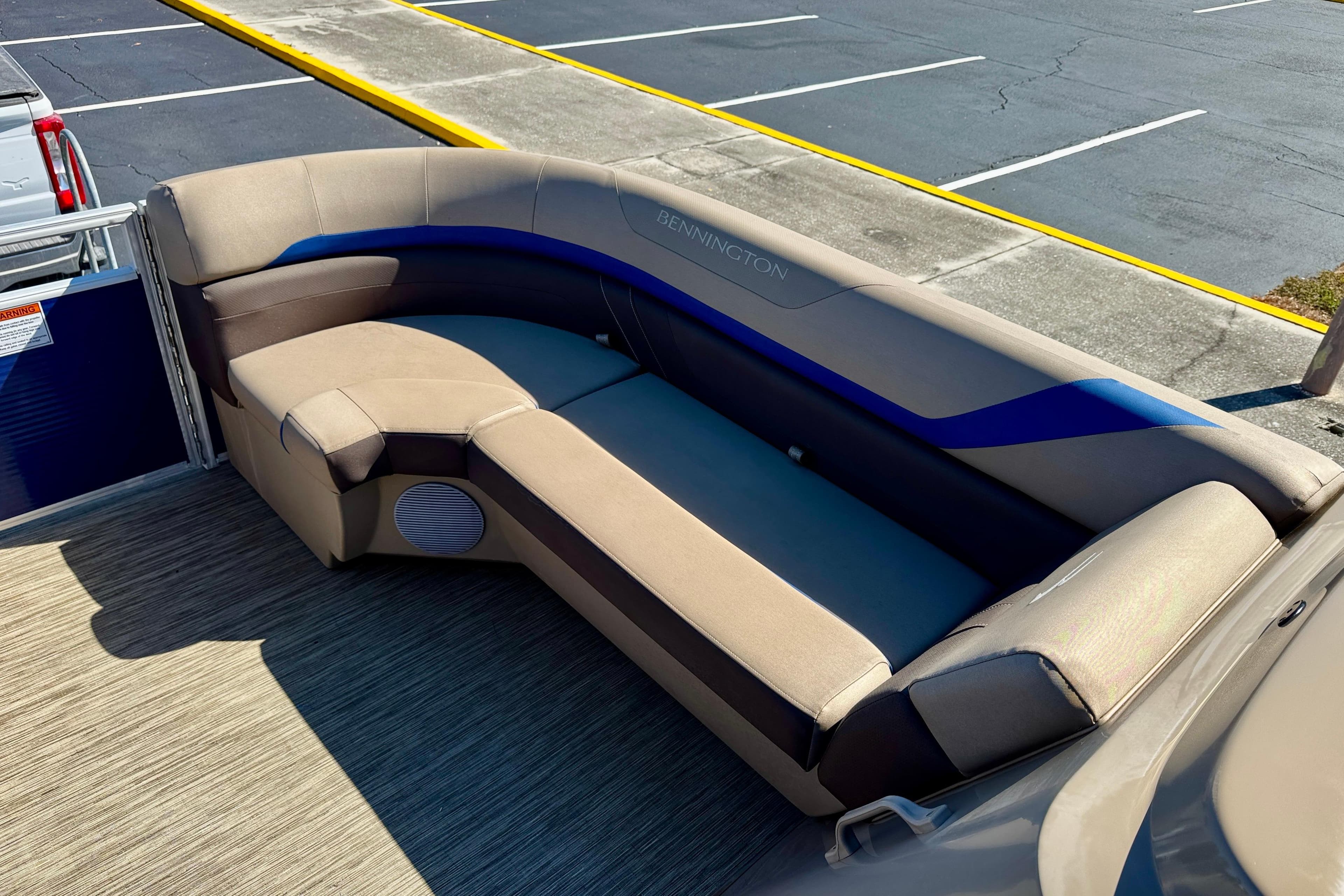 2023 Bennington 23 SX boat interior with beige and blue seating, parked on pavement.