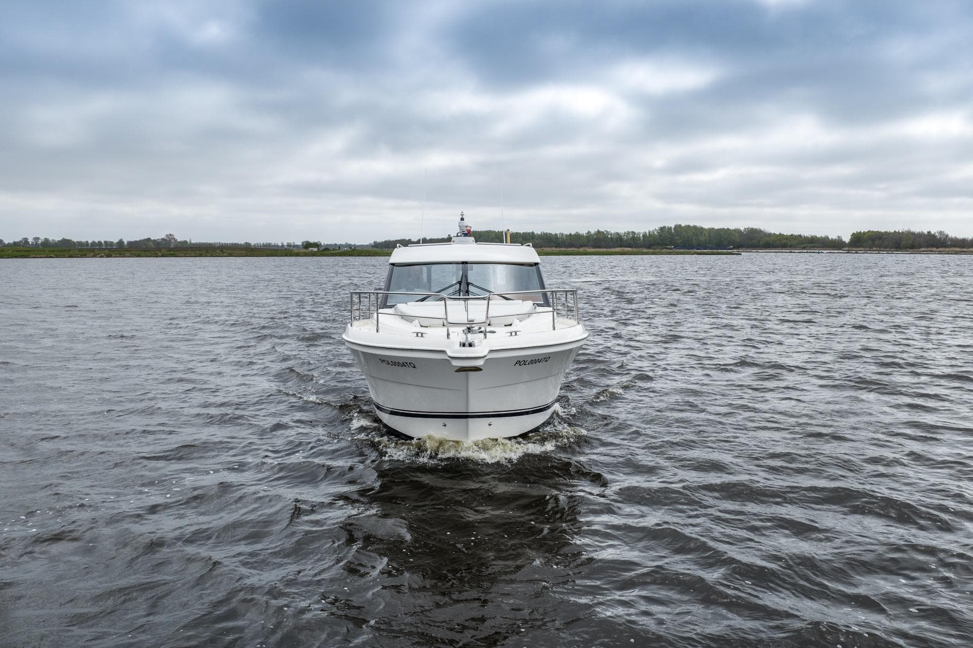 2010 Riviera 3600 Sport Yacht cruising on a calm lake under cloudy skies.