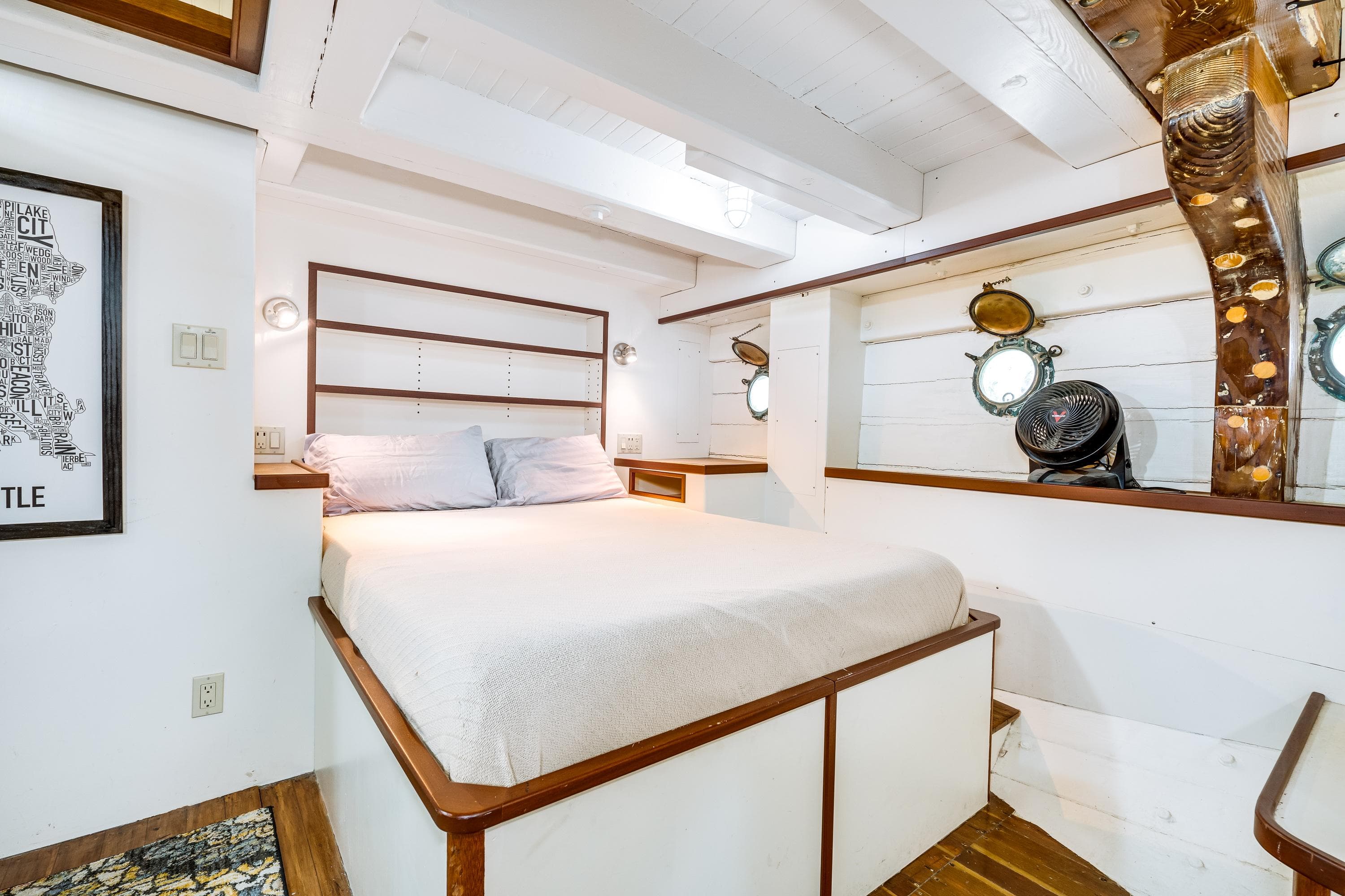Cozy bedroom in 1941 Custom Sagstad Fantail boat with nautical decor and porthole windows.