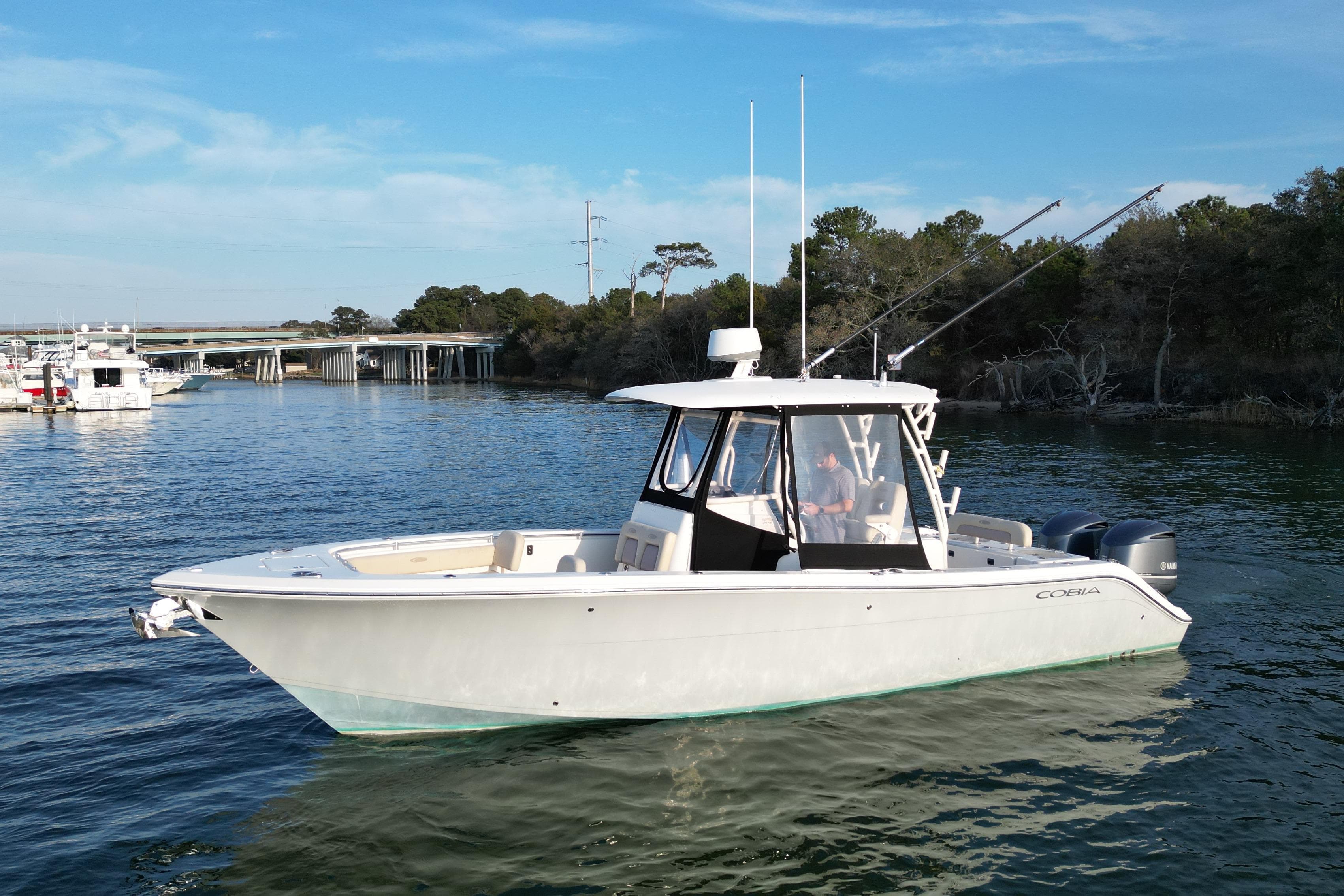 2016 Cobia 296 Center Console boat on calm water, with scenic background.