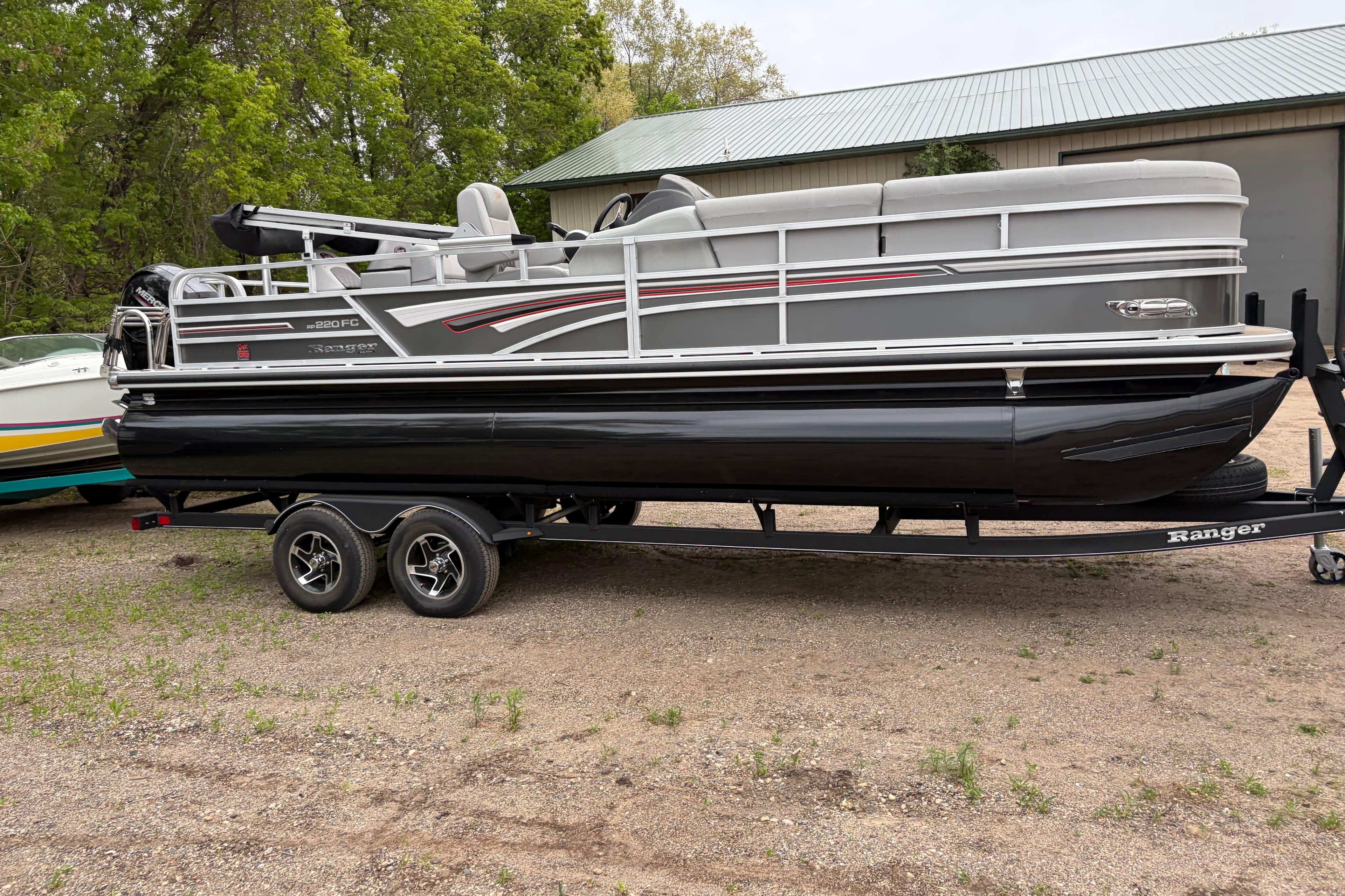 2023 Ranger 220FC pontoon boat on trailer, parked outdoors near a building.