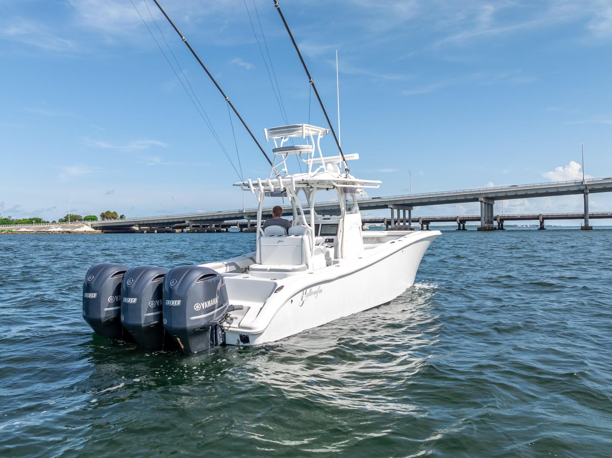 2021 Yellowfin 34 boat with triple Yamaha engines on open water near a bridge.