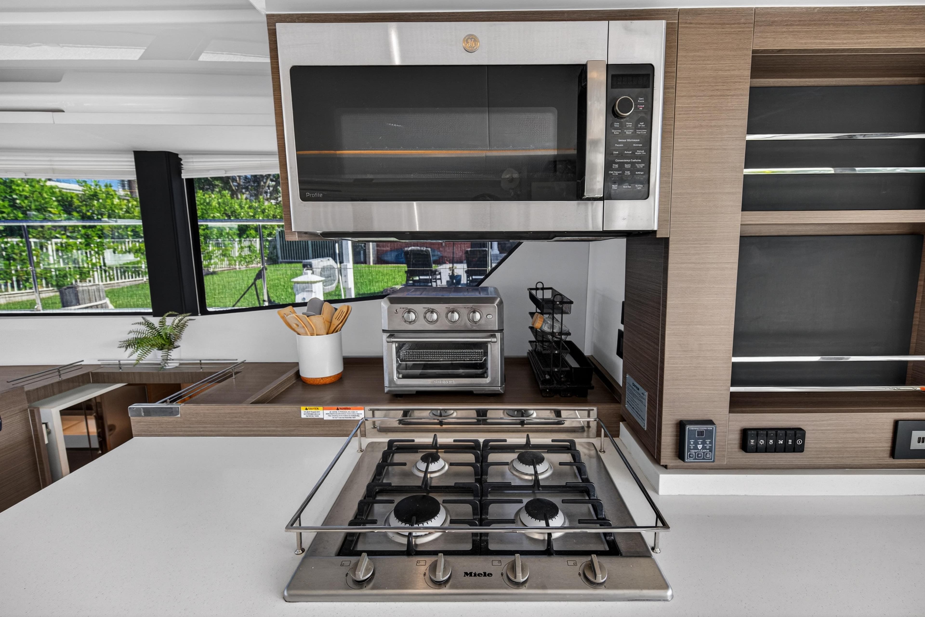 Modern kitchen in 2022 Leopard 53 Powercat with stove, microwave, and sleek cabinetry.