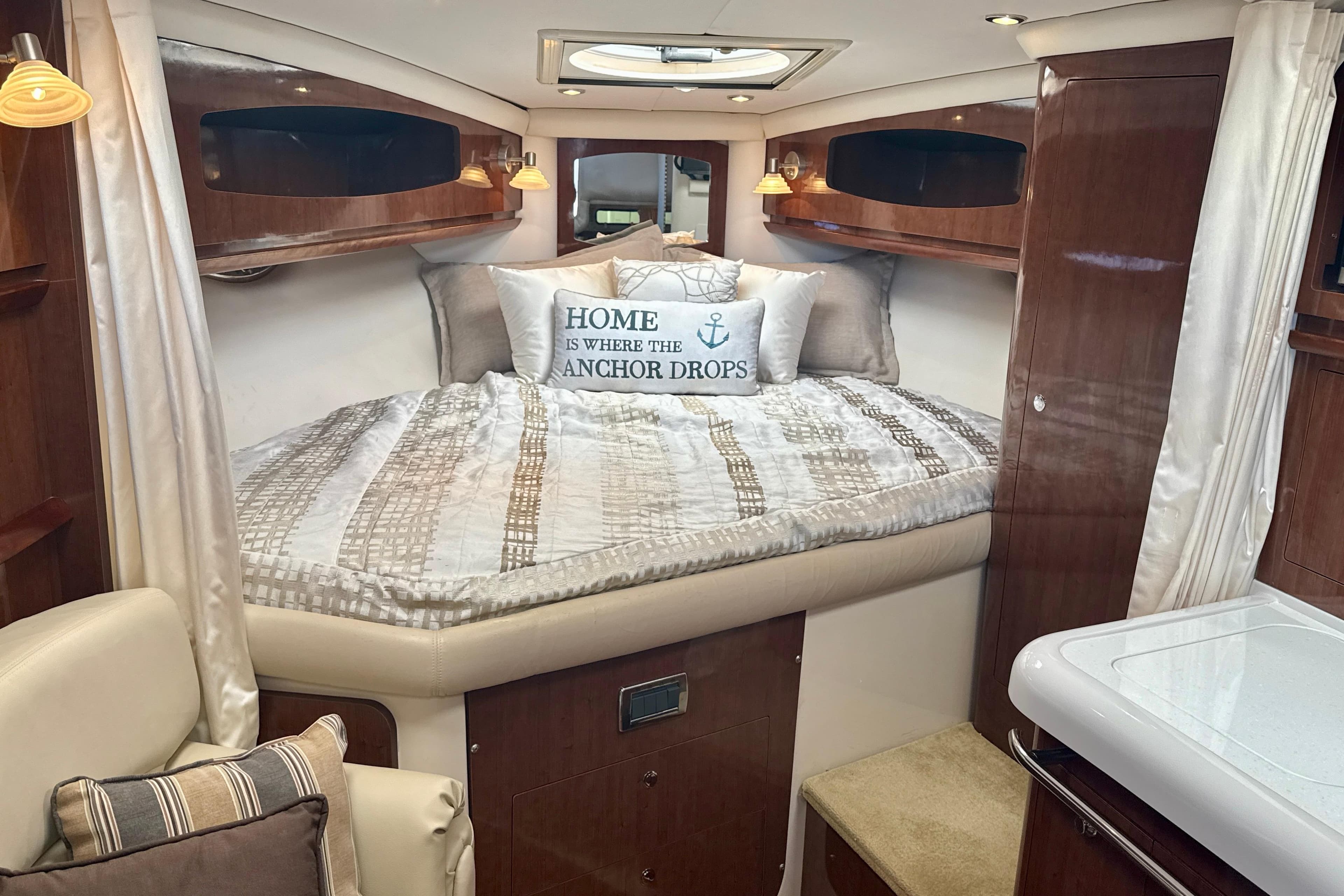 Luxurious 2016 Four Winns V335 cabin interior with cozy bed and nautical decor.