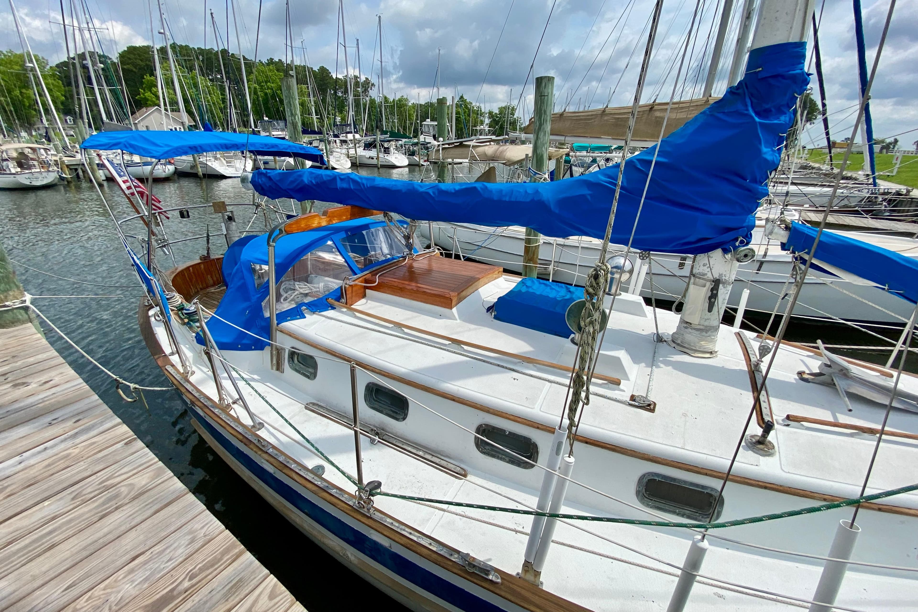 Sailboat docked at marina, Union EO 32 model, 1981, with blue covers and wooden accents.