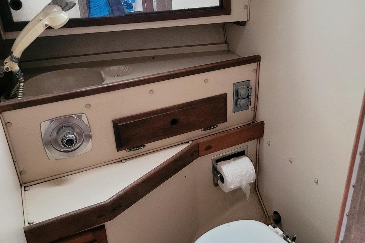 Compact bathroom in a 1984 Newport 28 sailboat with sink and toilet.