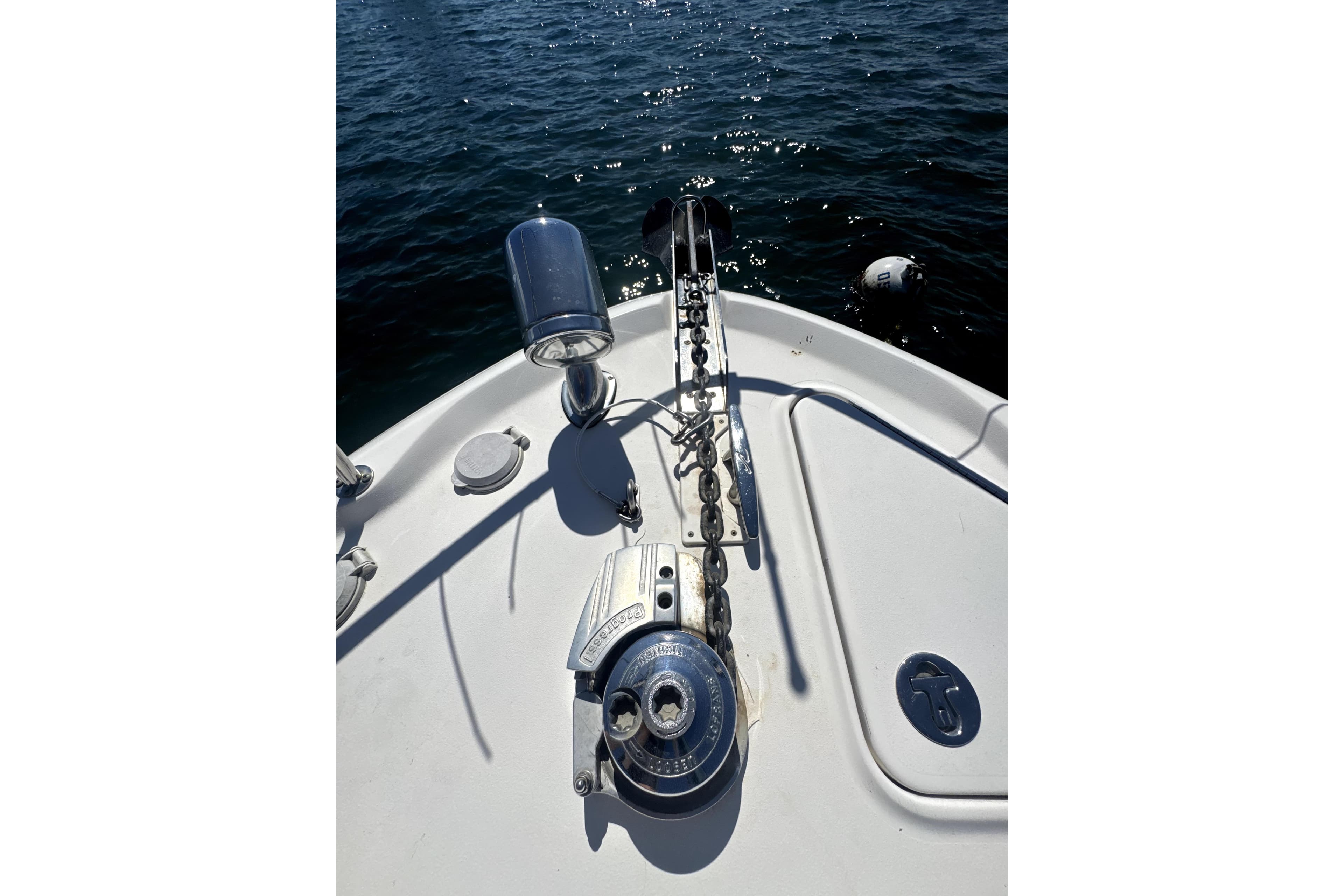 Bow of 2002 Sea Ray 340 Sundancer with anchor chain and winch, on water.