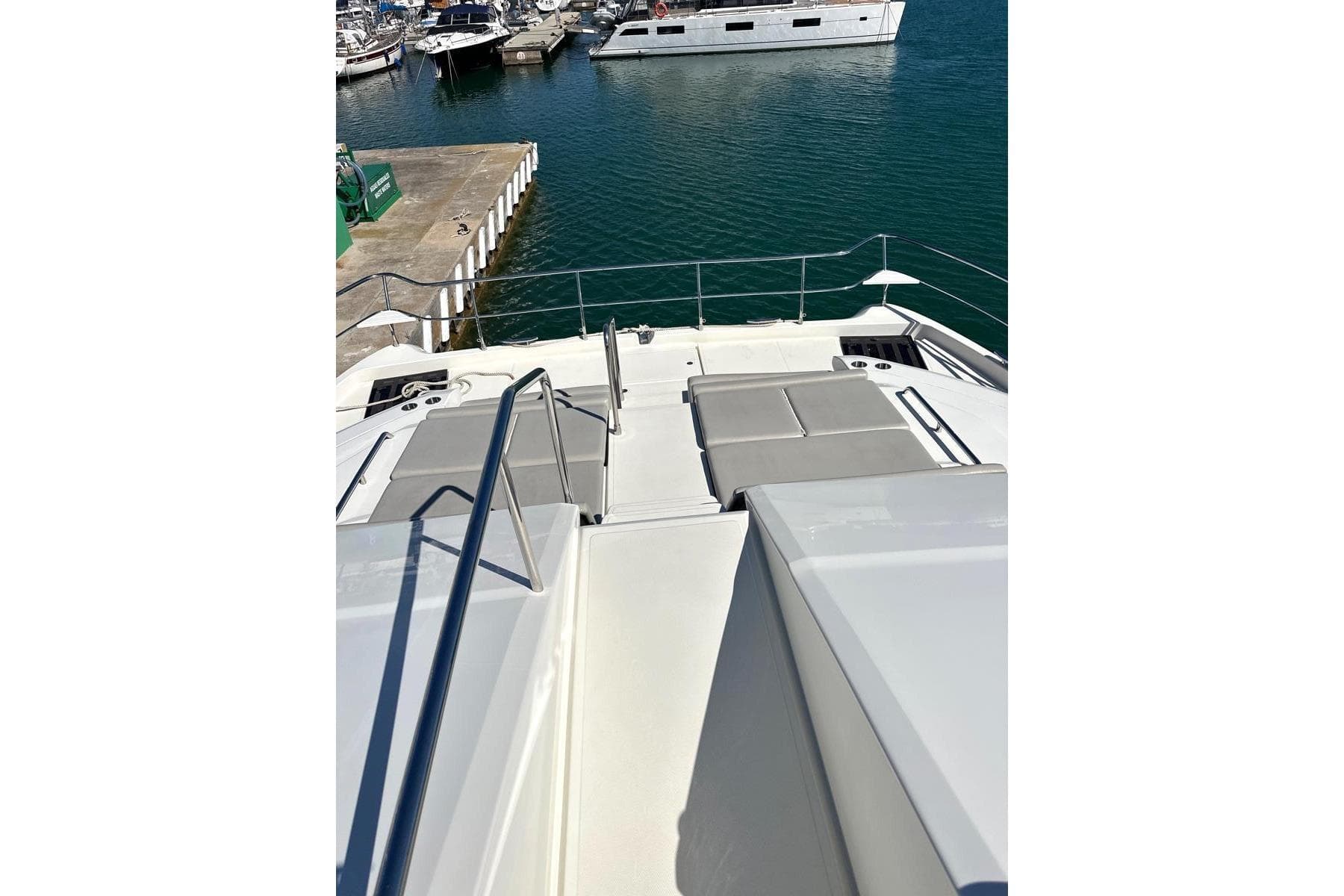 Aquila 54 Yacht 2022, docked with sunbathing area, overlooking marina.