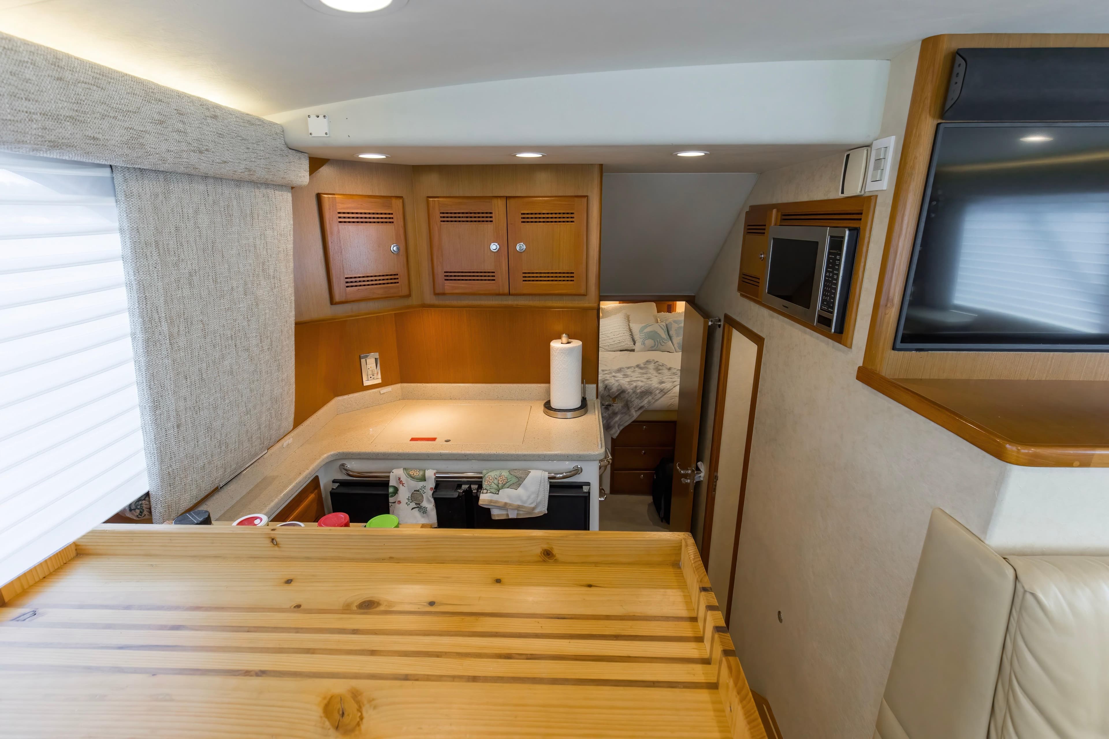 Interior of 2005 Cabo 40 Flybridge yacht with kitchen and cozy sleeping area.