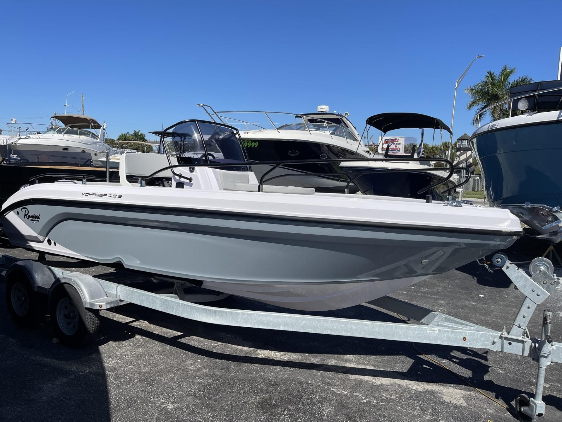 2024 Ranieri Voyager 19S boat on trailer, parked in marina under clear blue sky.