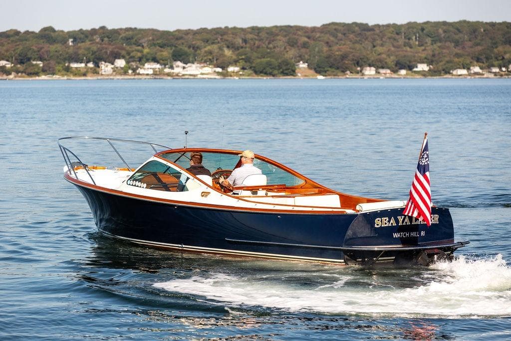 2003 Hinckley T29R boat cruising on a calm lake with American flag.