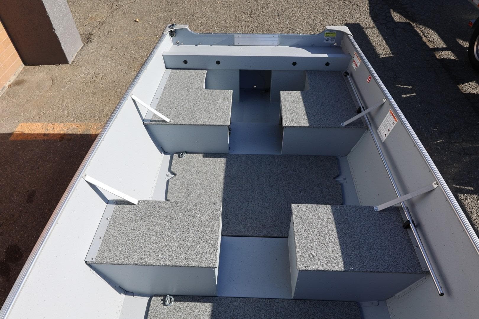 2026 Lund SSV-16 Tiller boat interior with gray seating and storage compartments.