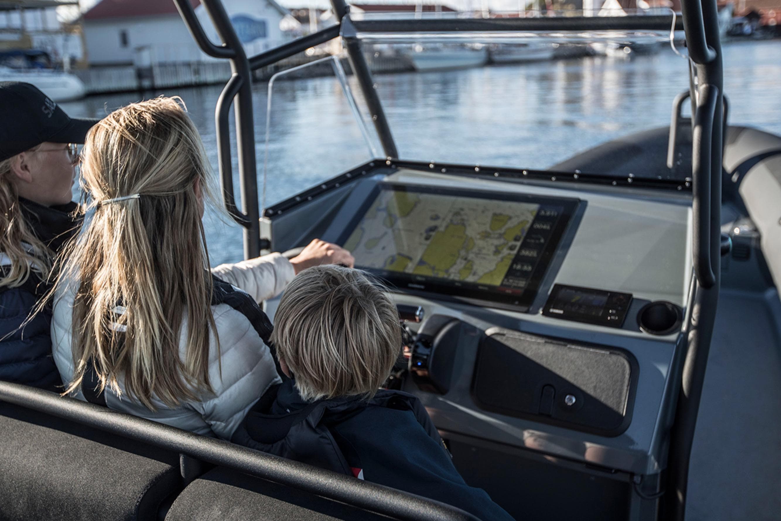 Family navigating on a 2026 Rupert R8 boat using a digital map display.