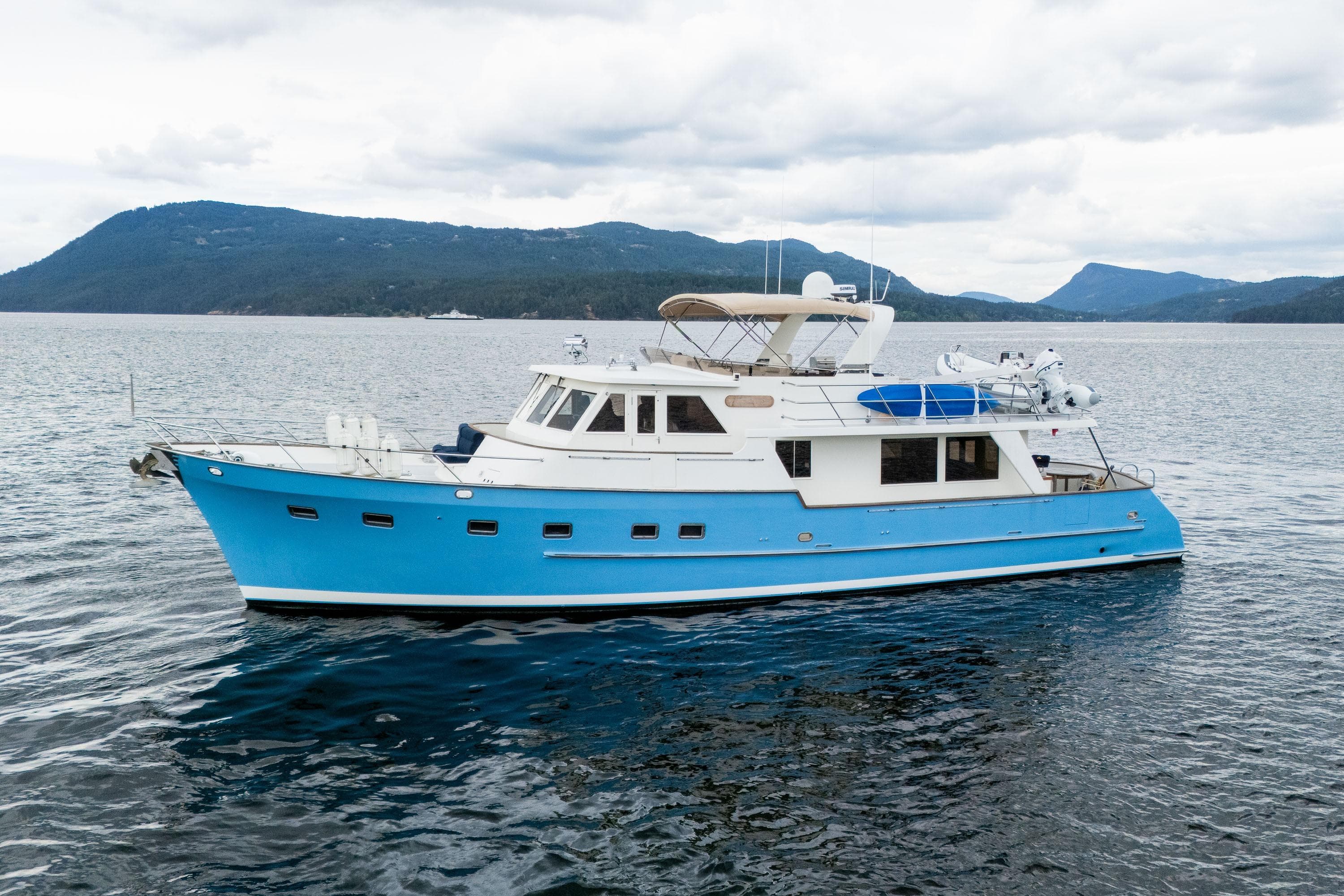 2000 Grand Alaskan Pilothouse Trawler on serene waters with mountainous backdrop.