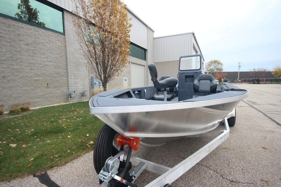 2025 Weldcraft 200 Rebel Open boat on trailer, parked outside industrial building.