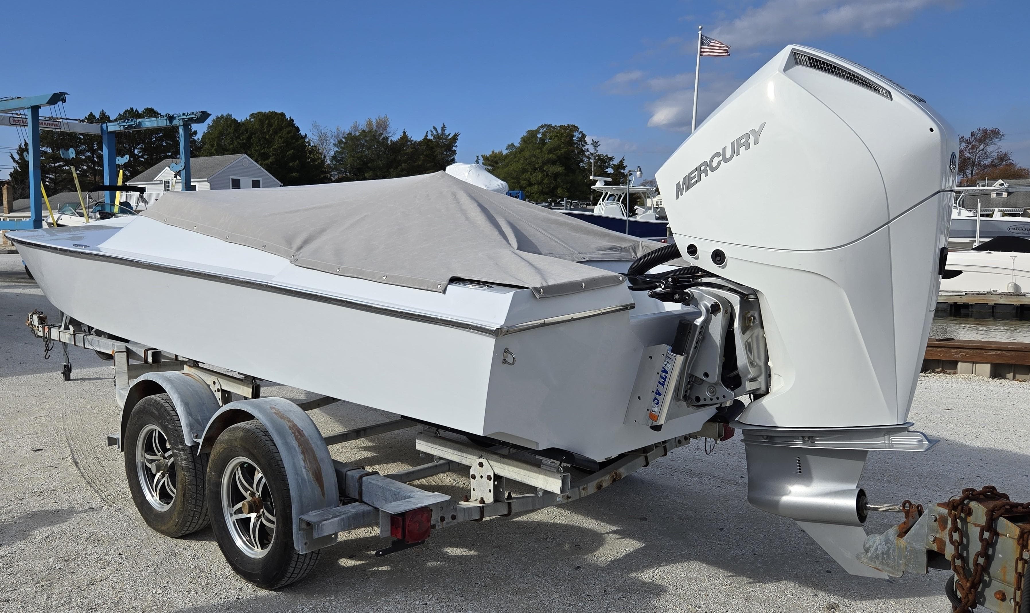 1991 Activator 22 boat on trailer with Mercury outboard motor, covered and parked outdoors.