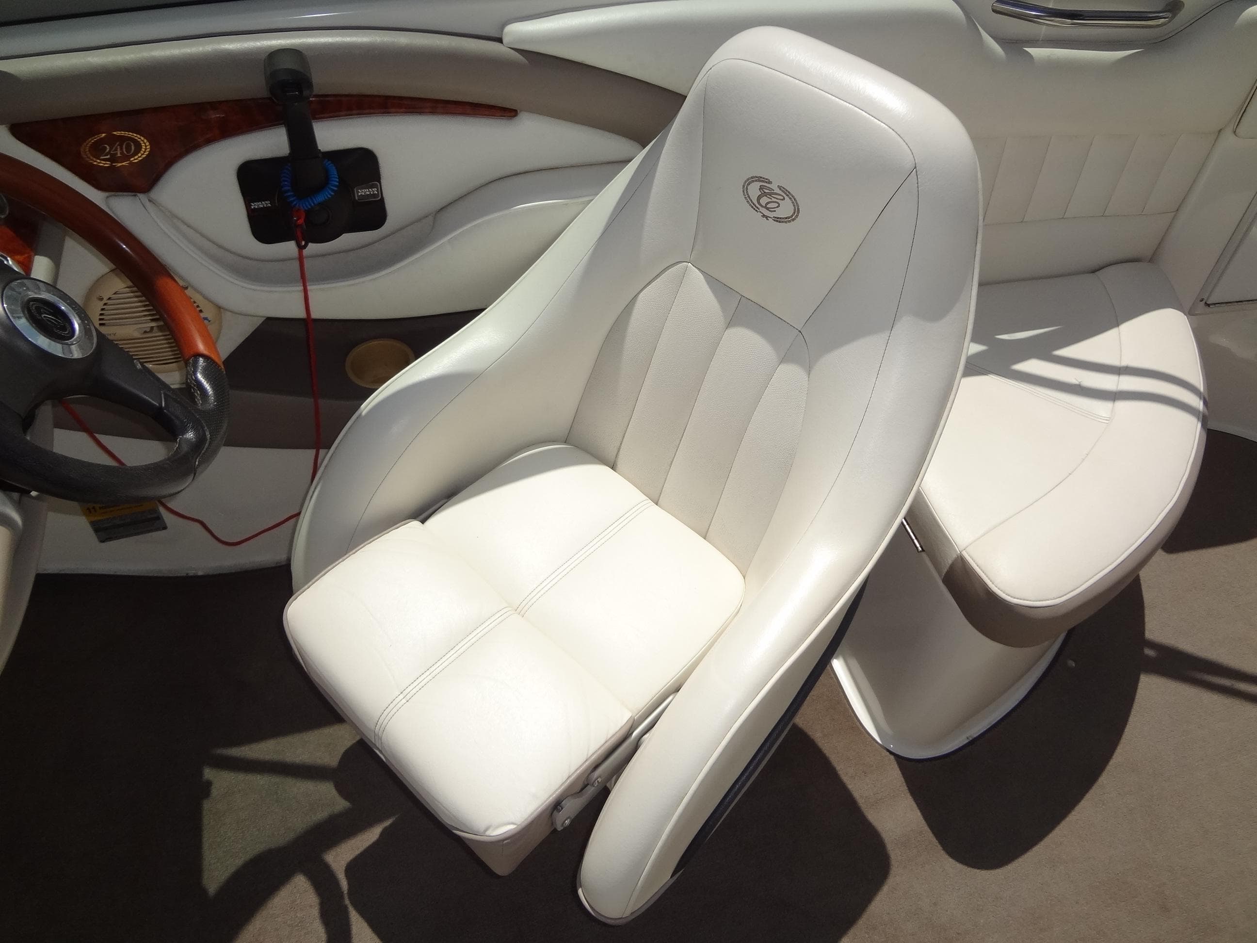2004 Cobalt 240 boat interior with white leather seating and wooden steering accents.
