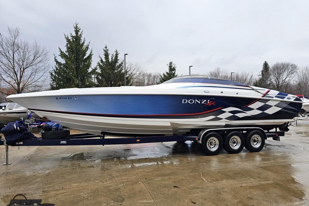 2000 Donzi 33 ZX speedboat on trailer, blue and white design, parked outdoors.
