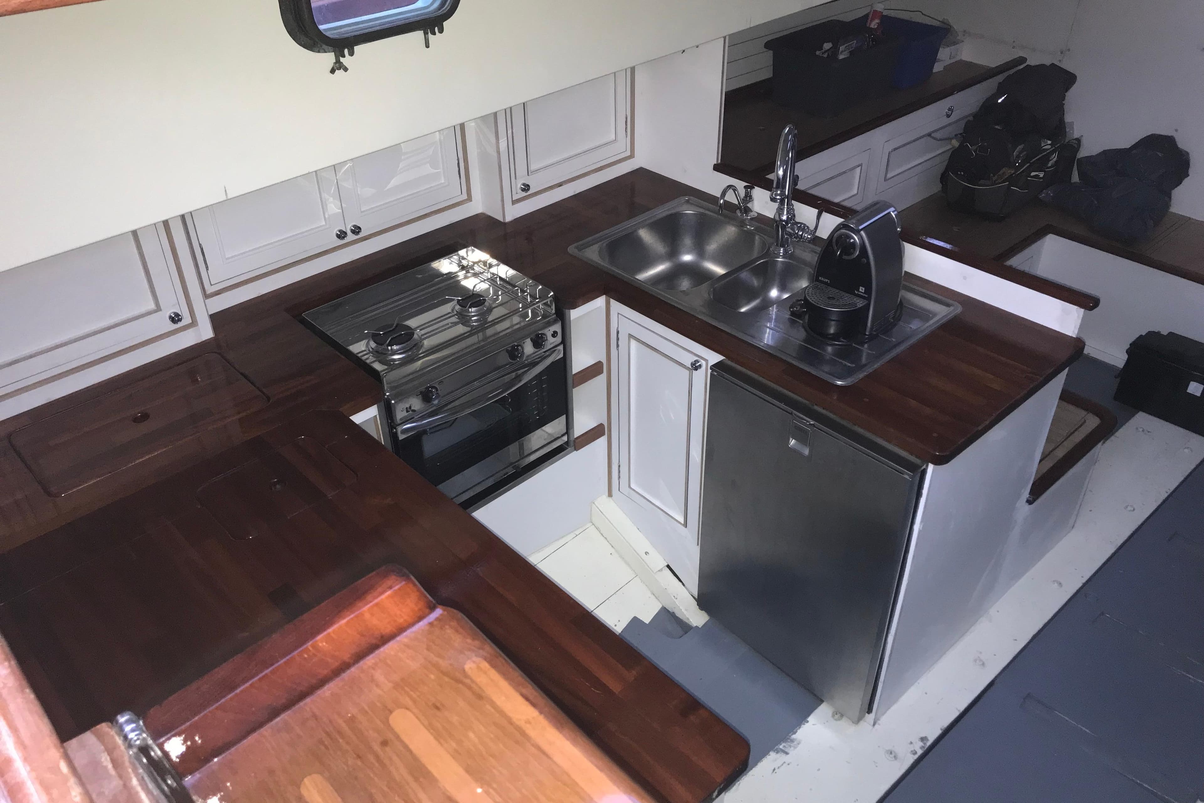 Interior of 1953 Herreshoff 58 yacht kitchen with wooden countertops and modern appliances.