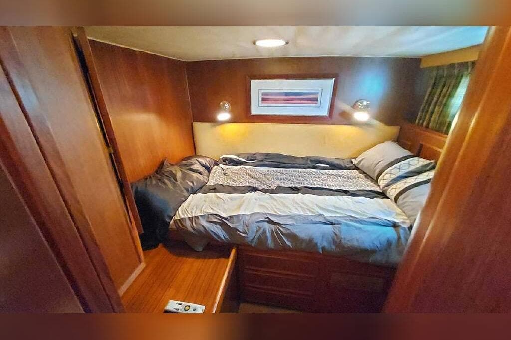 Cozy bedroom in 1983 Hatteras 53 Extended Deckhouse Motor Yacht with wood paneling and soft lighting.