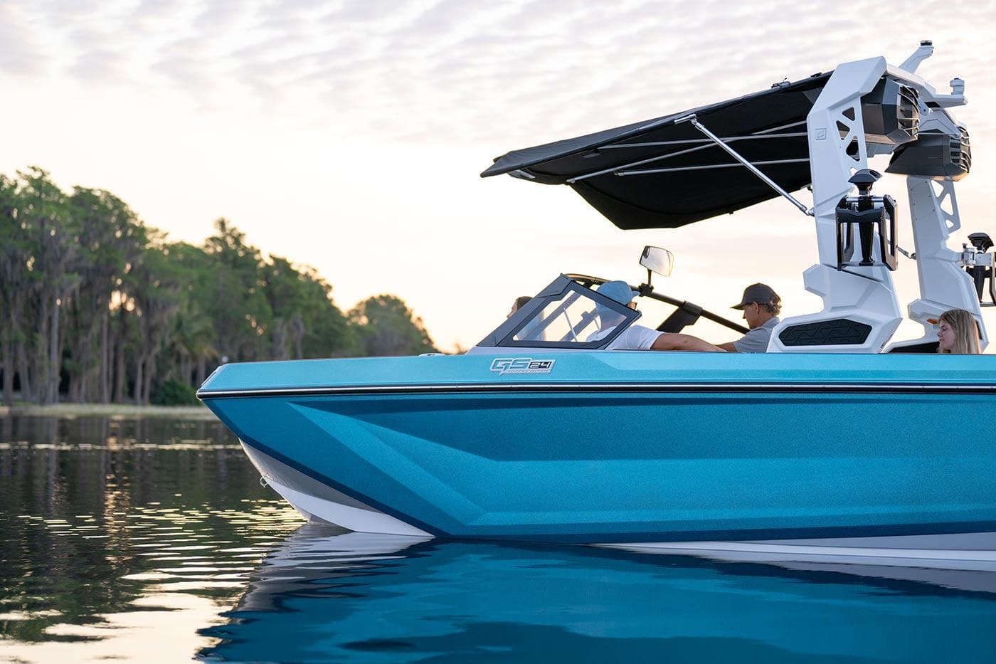 Nautique Model Year 2024 GS24 boat on calm water, side view, with trees in background.
