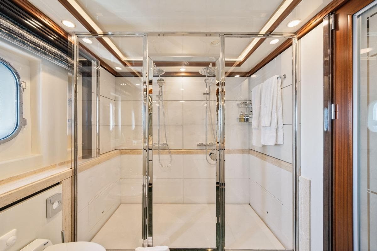 Luxurious yacht bathroom with glass shower, elegant wood accents, and modern fixtures on CRN Magnifica 2001.