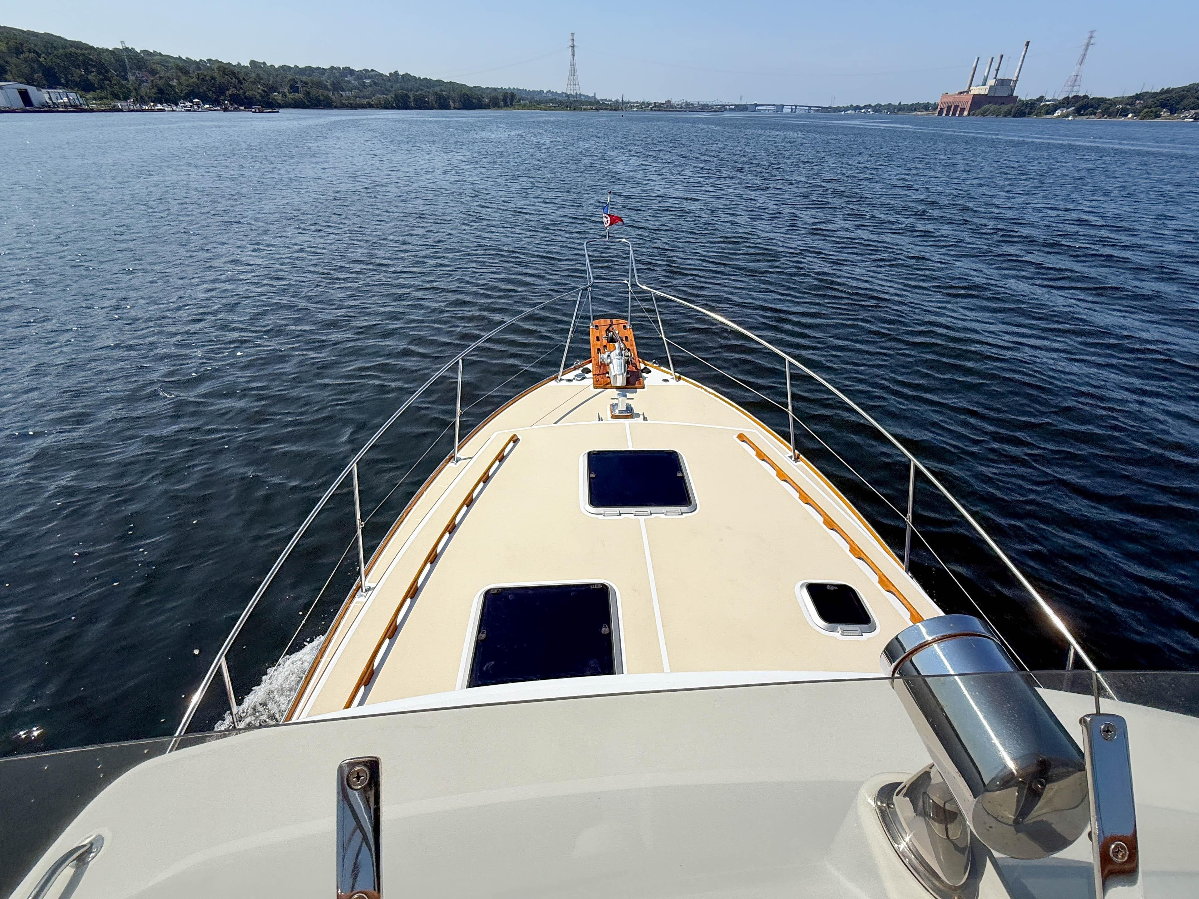 1984 Wilbur 38 boat cruising on a calm river with scenic shoreline views.