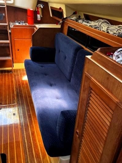 1986 Pearson 303 yacht interior with blue sofa and wooden flooring.