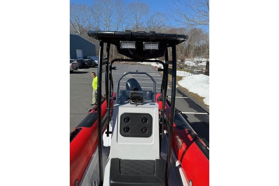 2024 Inmar 660-DR boat with red sides, parked outdoors on a sunny day.
