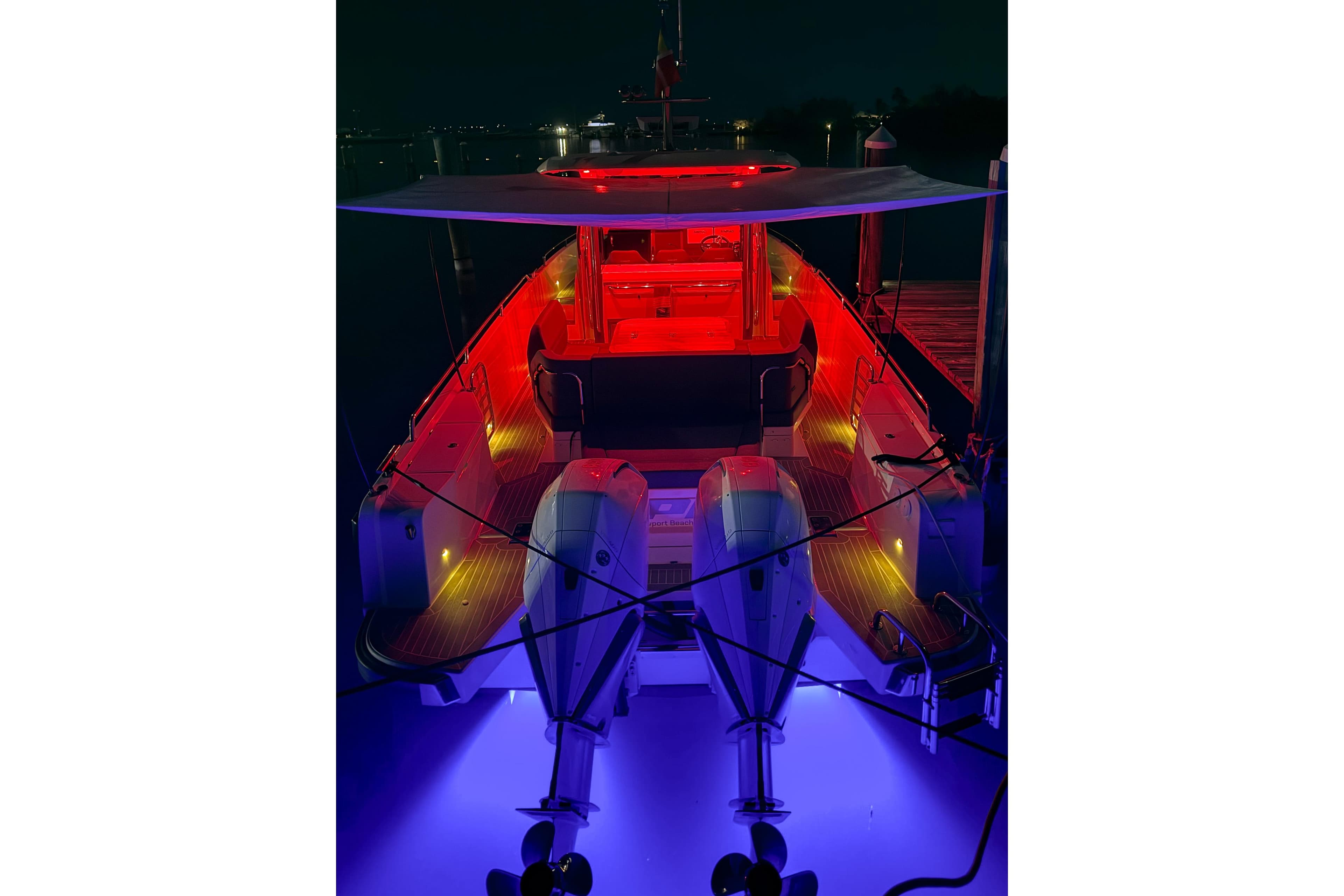 Nimbus T11 2022 boat illuminated with vibrant red and blue lights at night.