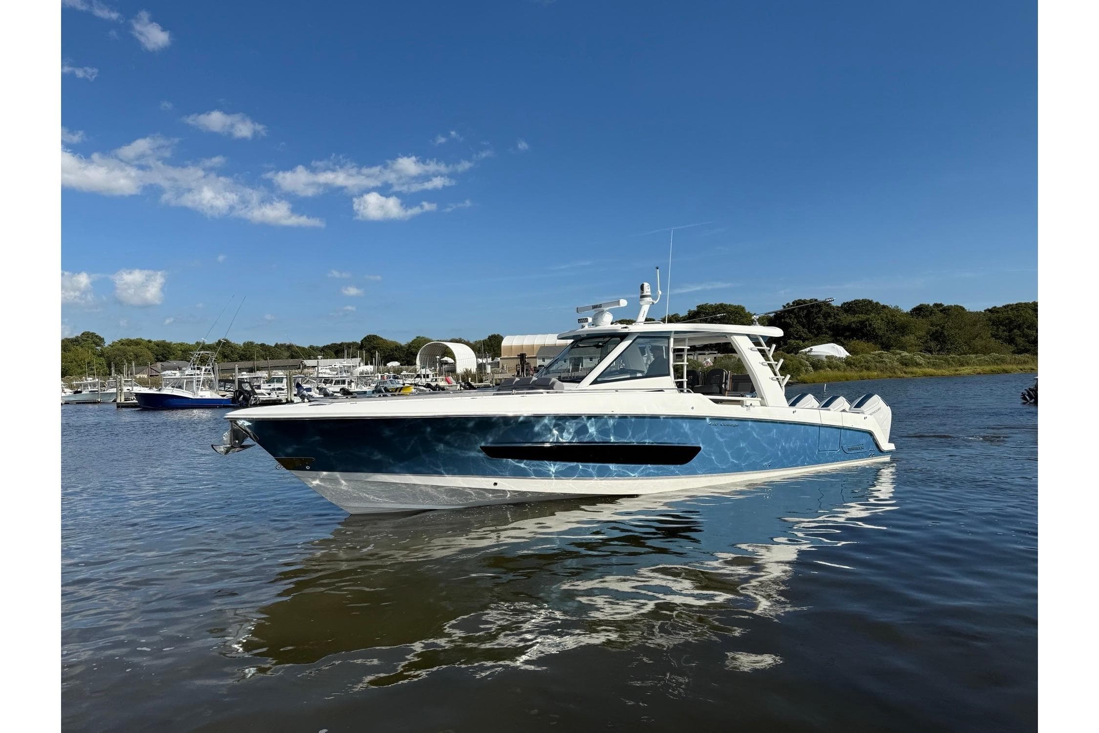 2024 Boston Whaler 420 Outrage boat on calm water under clear blue sky.
